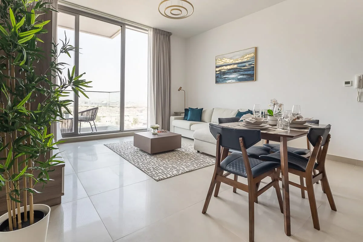A bright living and dining area with seating beside large windows.