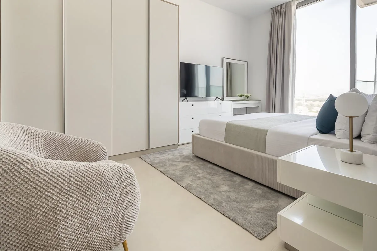 A bright bedroom with a bed, built-in wardrobes, and a television.