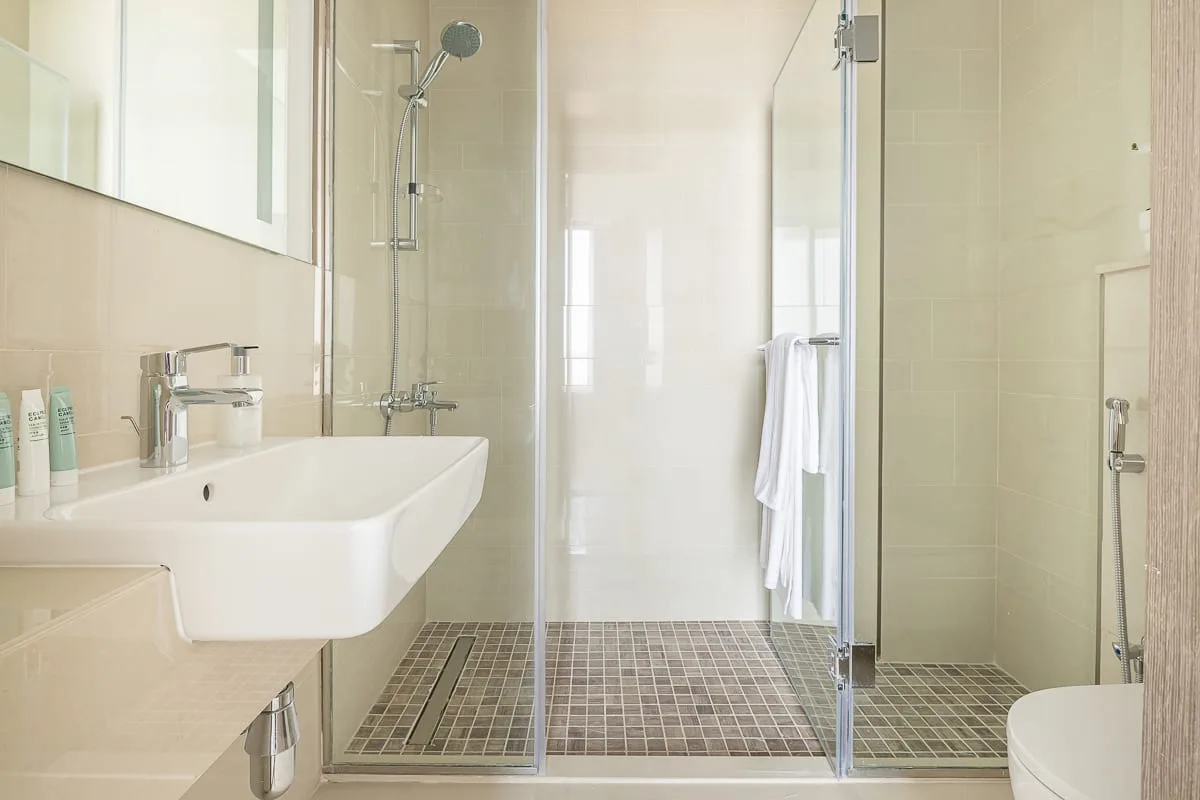 A bright bathroom with a glass-enclosed shower and wall-mounted sink.