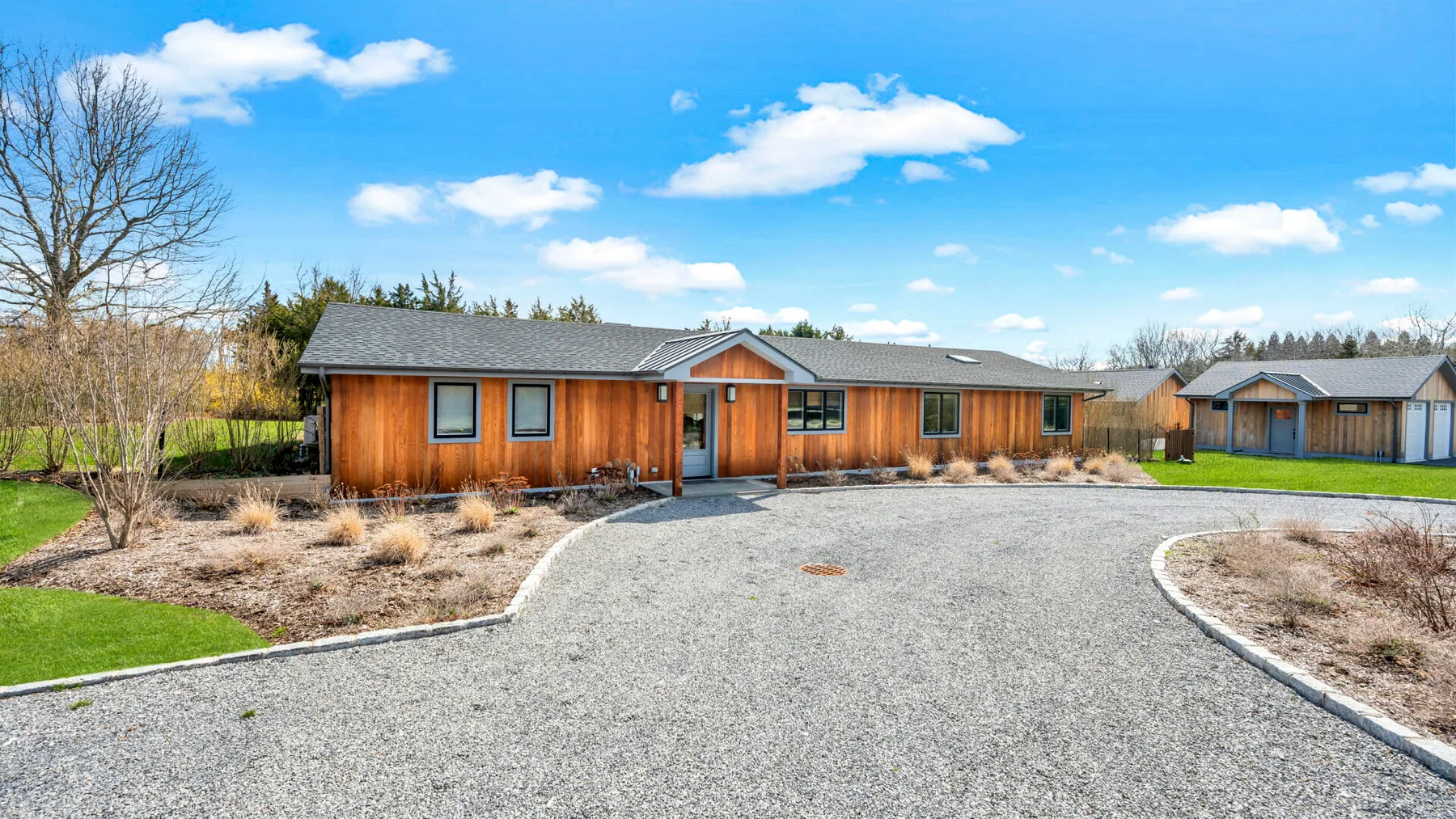 A low-rise building with wood siding faces a broad paved driveway.