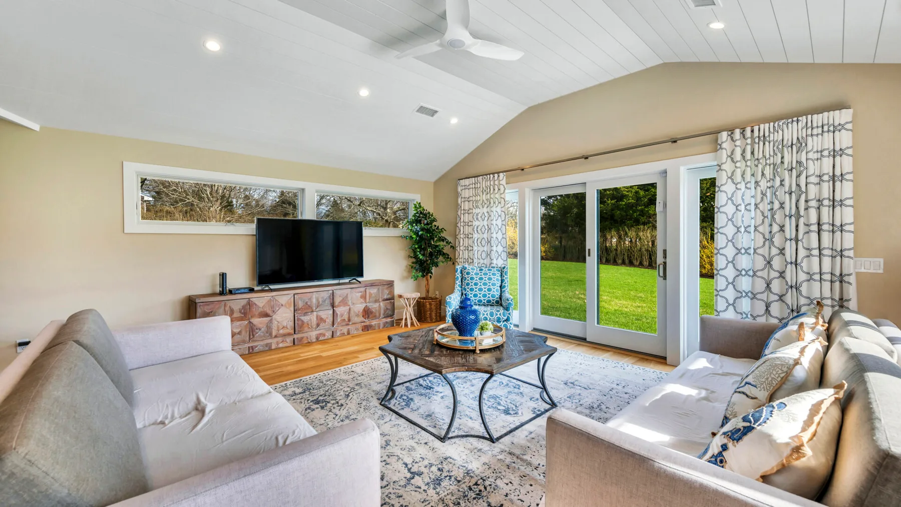 A bright living room with seating around a glass coffee table and large windows.