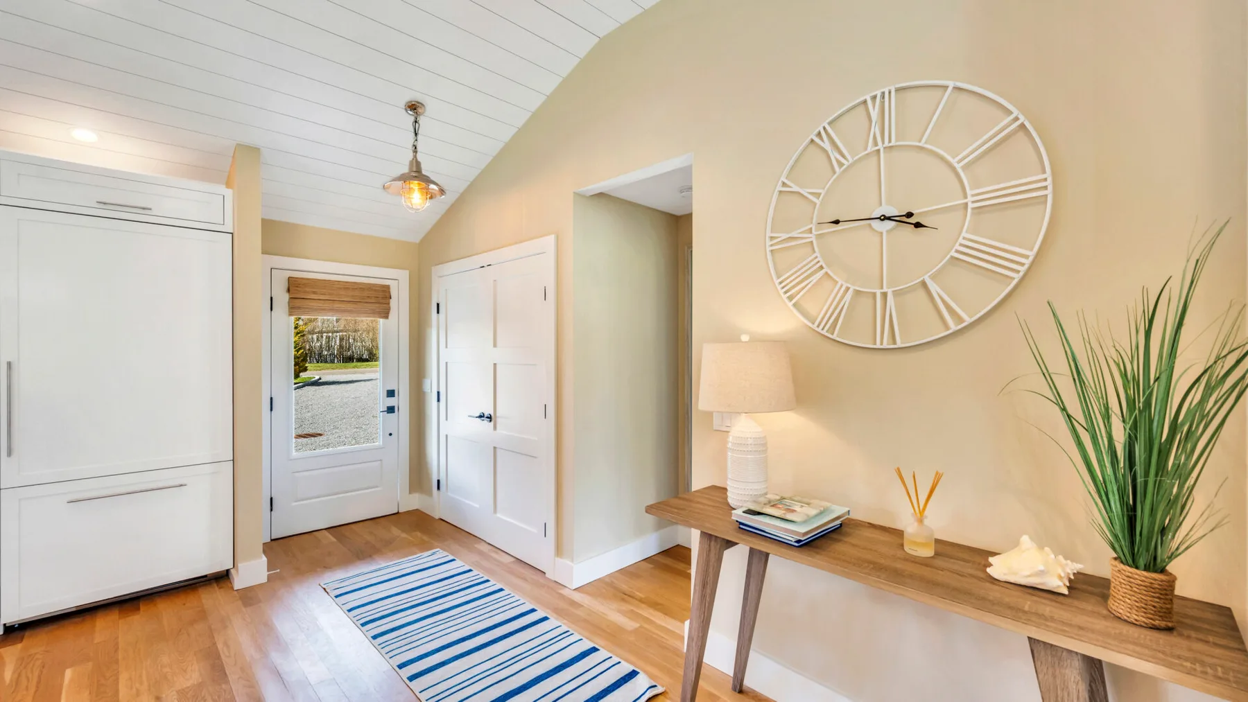 A bright entryway with white doors, a striped rug, and a wooden console table.