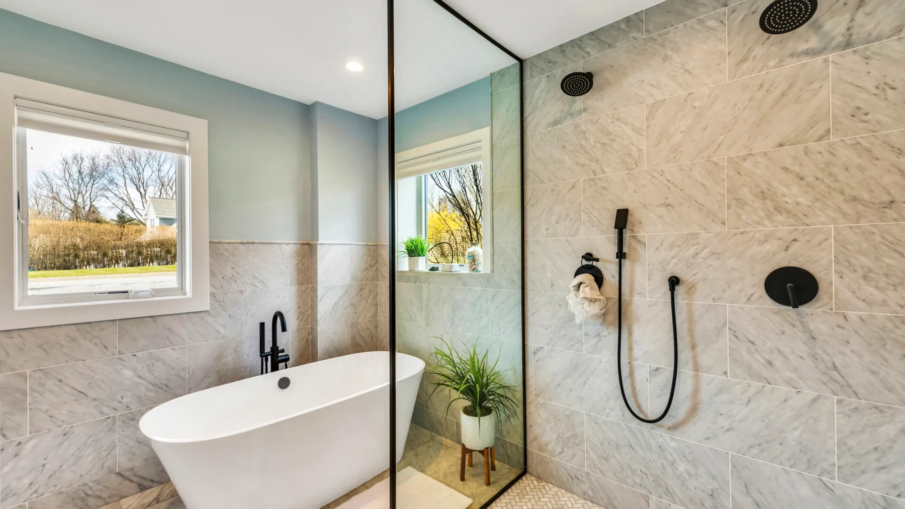 A bathroom with a freestanding bathtub and glass-partitioned shower.