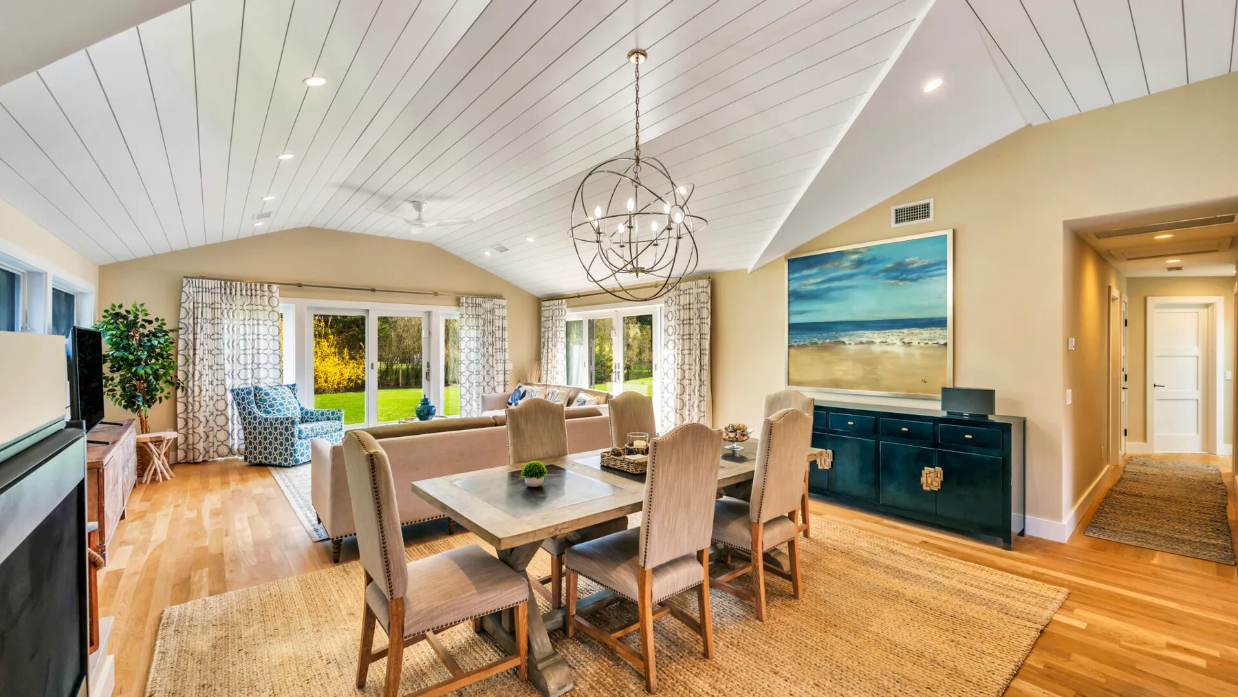 A dining area with a wooden table and chairs beneath a hanging light.