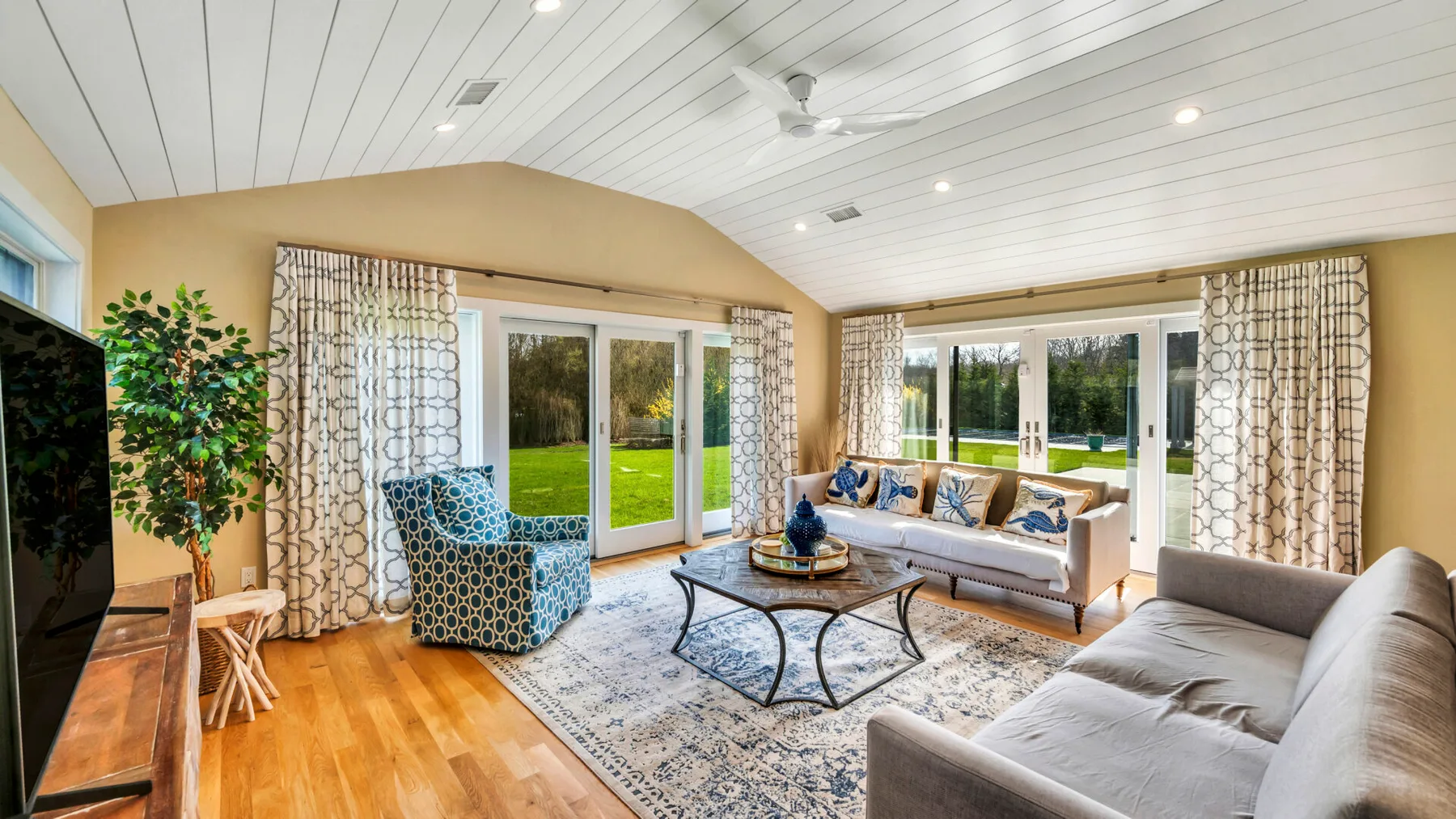 A bright living room with seating around a glass coffee table and large windows.