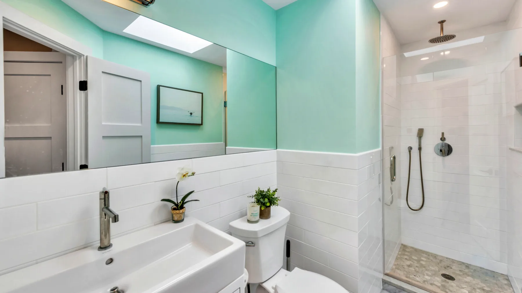 A bright bathroom with a sink, toilet, and walk-in shower.