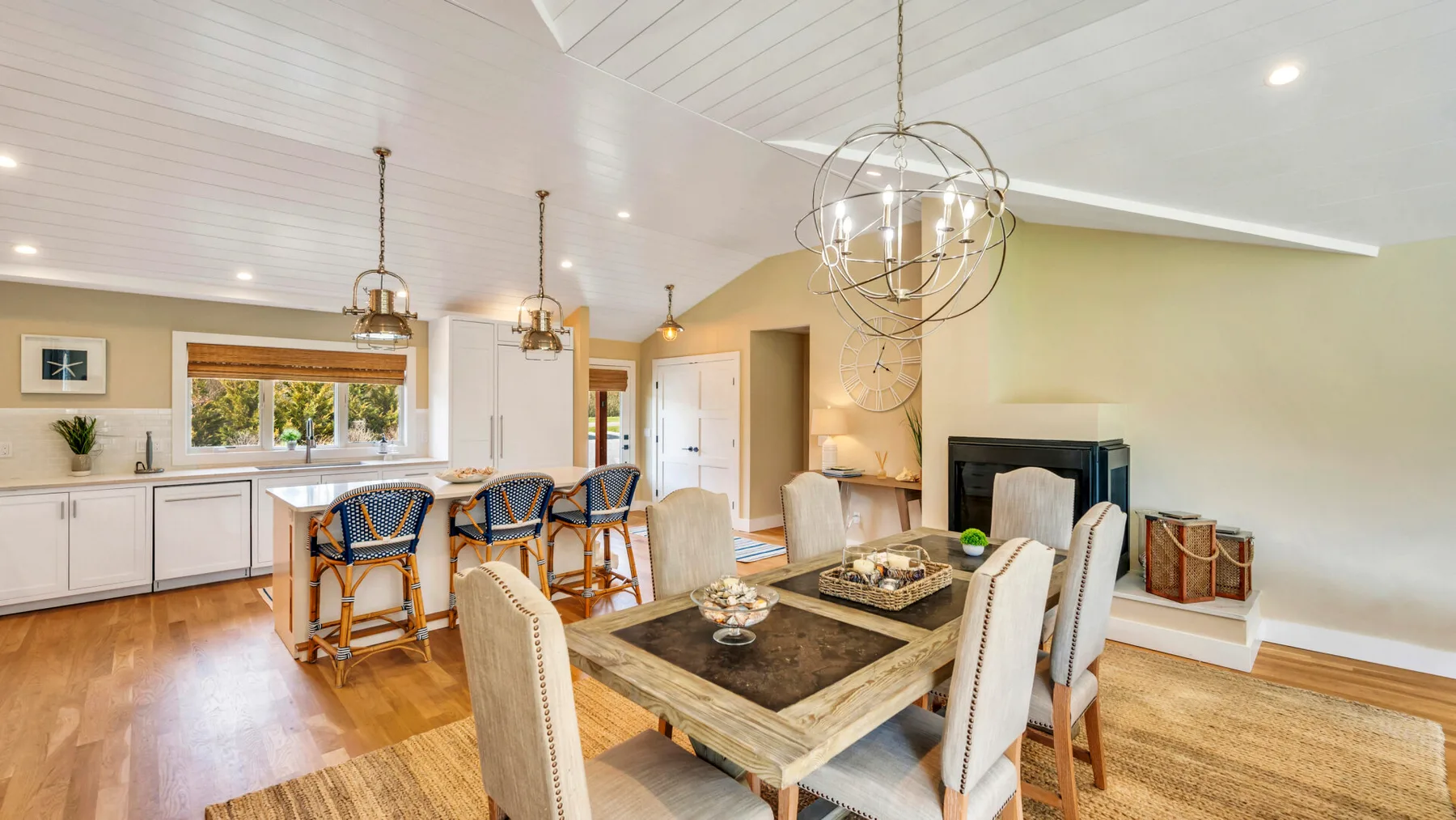 An open-plan kitchen and dining area with a table, seating, and a fireplace.