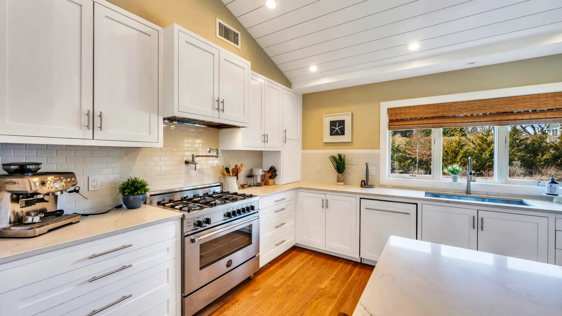 A bright kitchen with white cabinets, stainless steel appliances, and a central island.