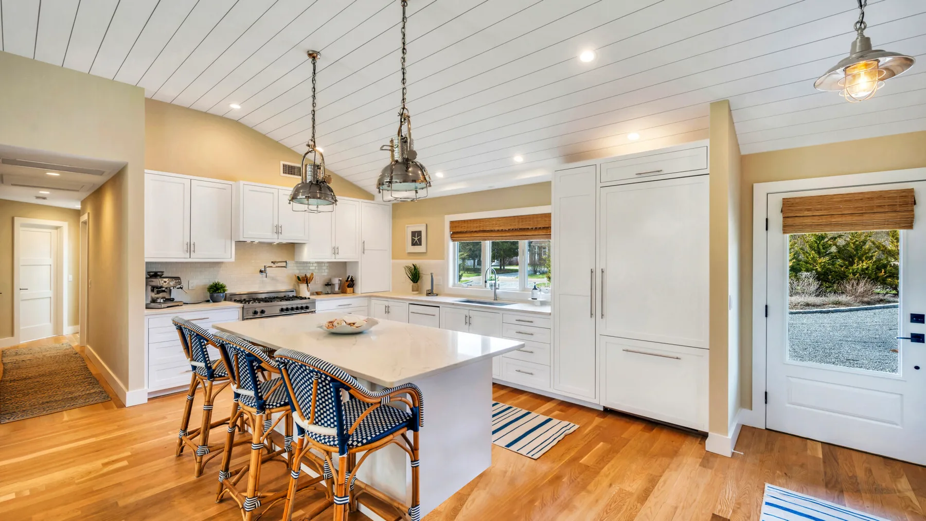 A bright kitchen with a large island, bar seating, and white cabinetry.