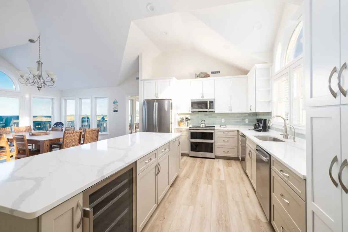 Una cocina luminosa con gabinetes blancos y una gran isla junto a un comedor.