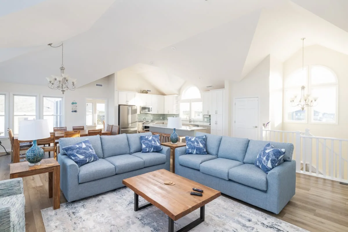 Una luminosa sala de estar con asientos azules y una mesa de centro de madera.