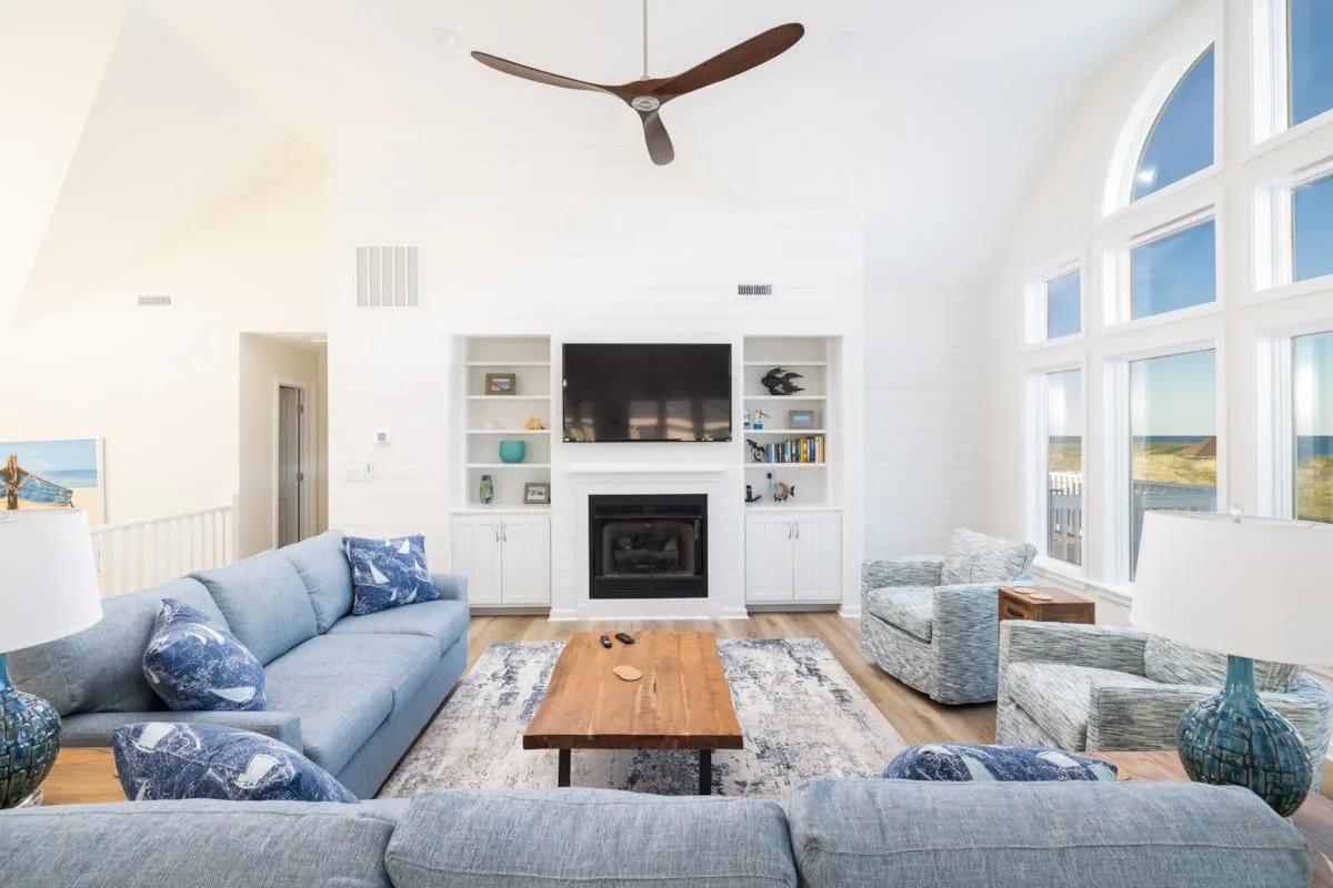 Una sala luminosa con asientos azules, una chimenea y ventanas altas.