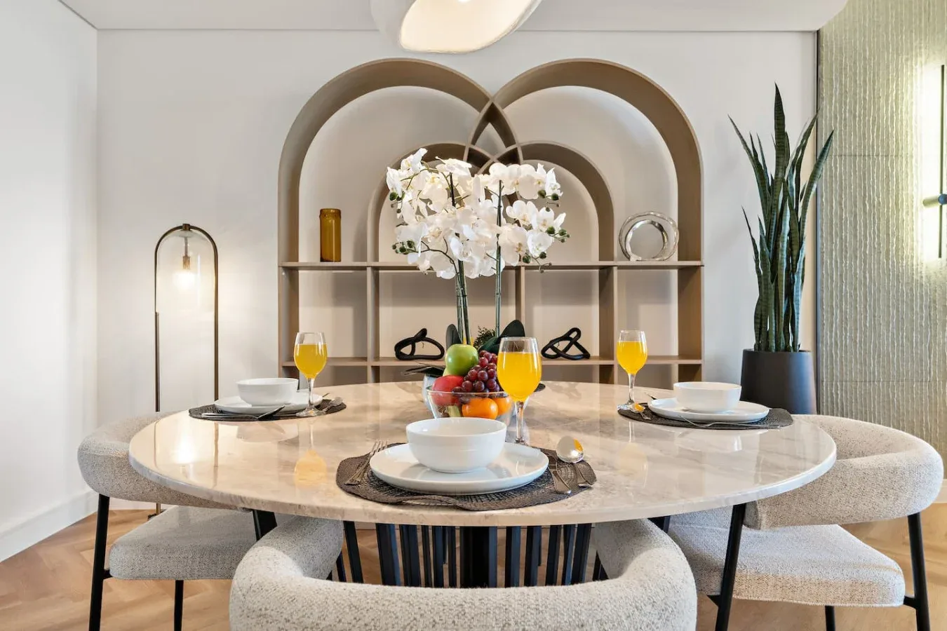 A dining area with a round table, upholstered seating, and flowers.