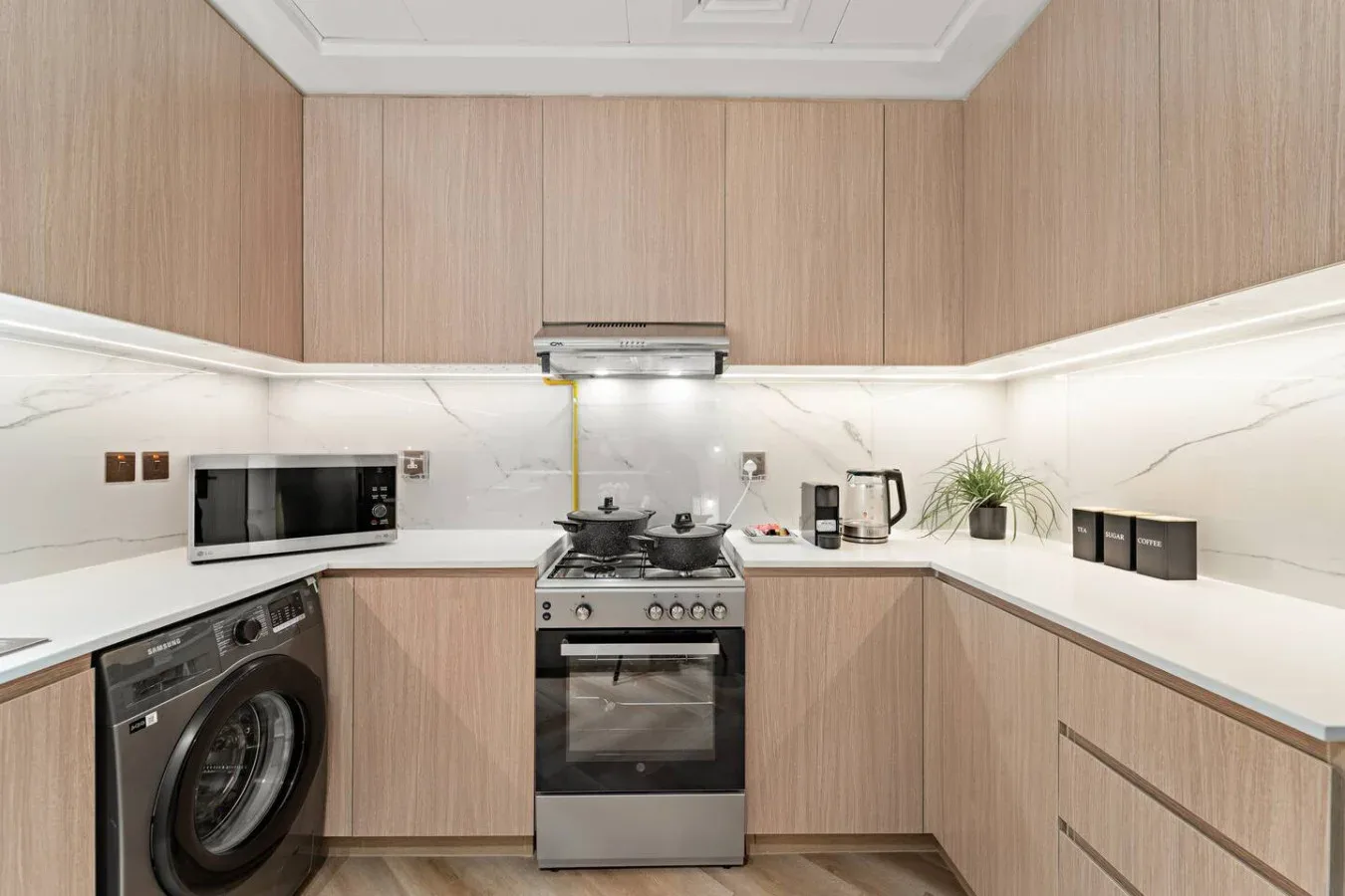 A modern kitchen with wood-toned cabinets, a stove, and countertop appliances.