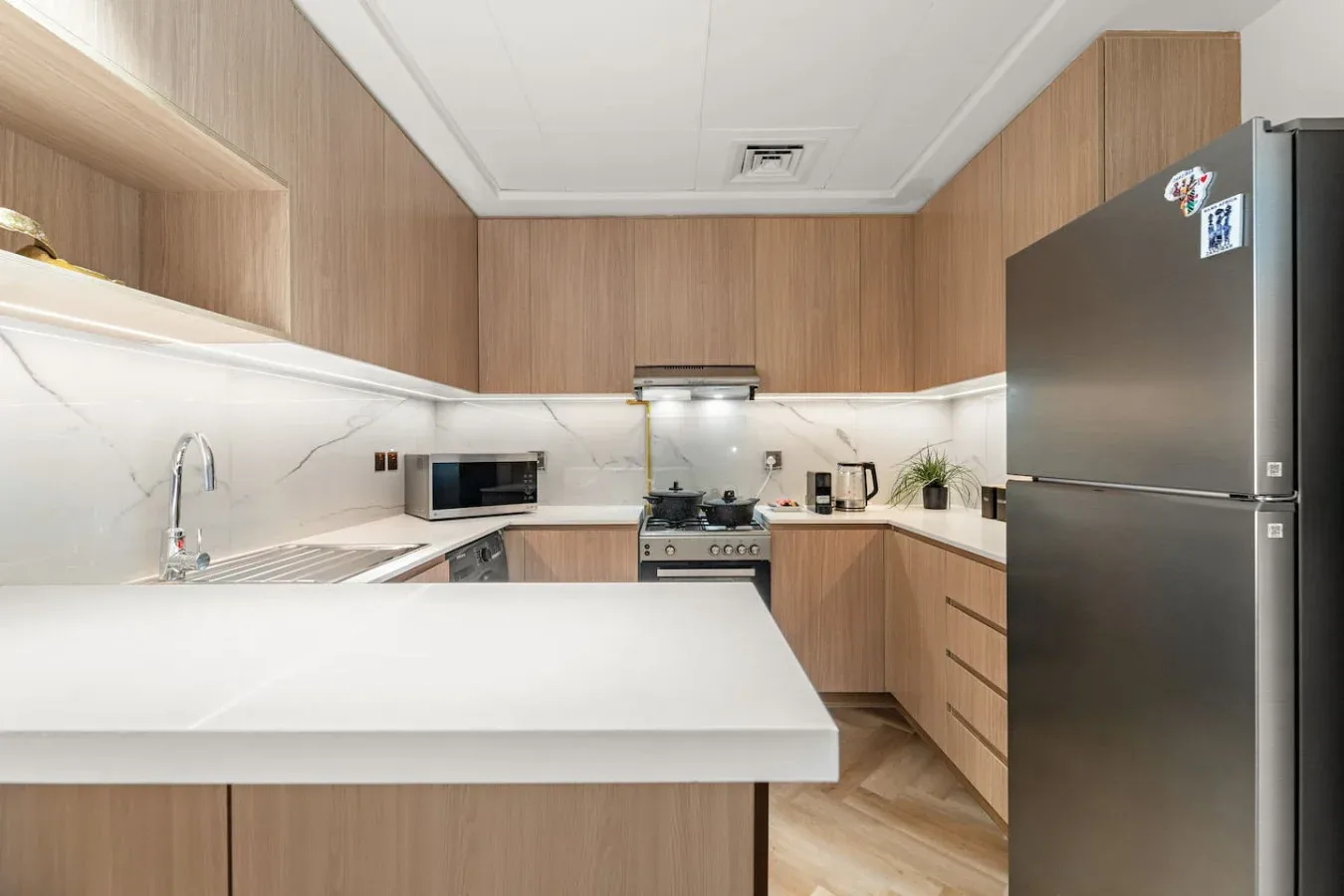 A compact kitchen with wood cabinetry, white counters, and a central island.