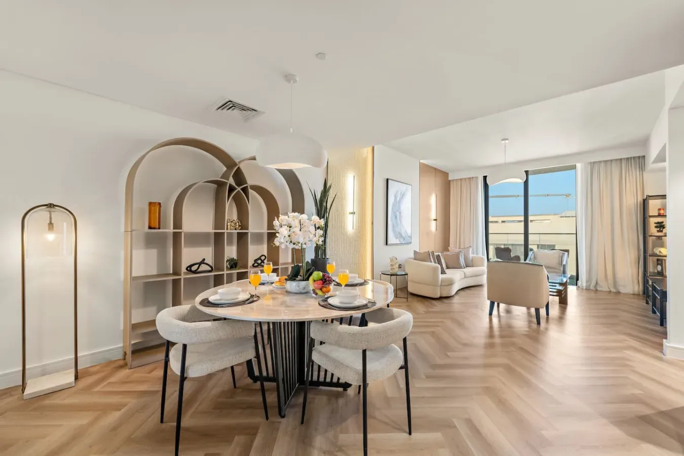 An open-plan dining and living area with a set dining table beside large windows.