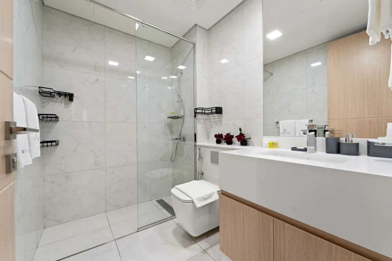A bright bathroom with a glass shower and a long vanity.