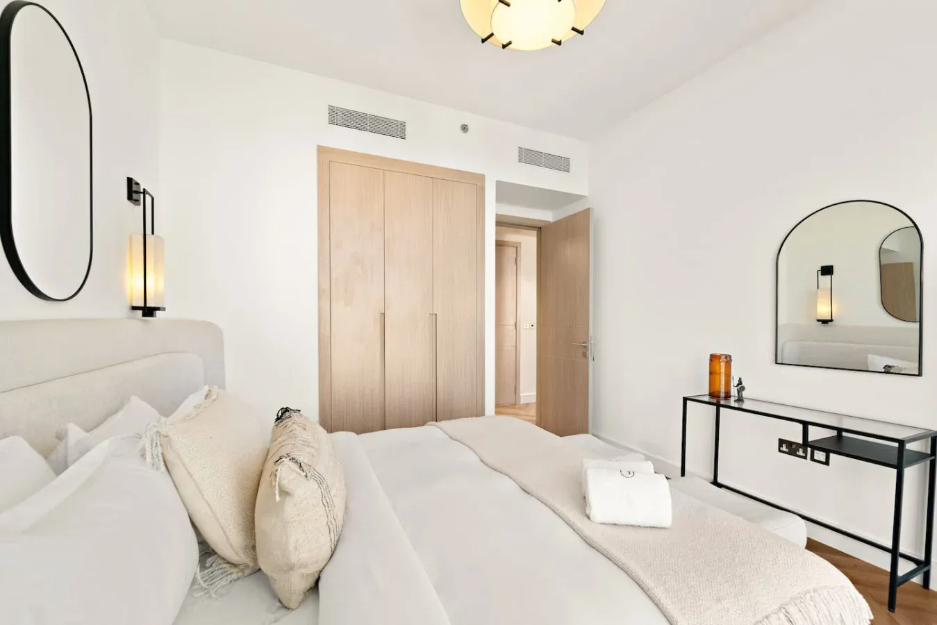 A bright bedroom with a large bed and light wood wardrobes.