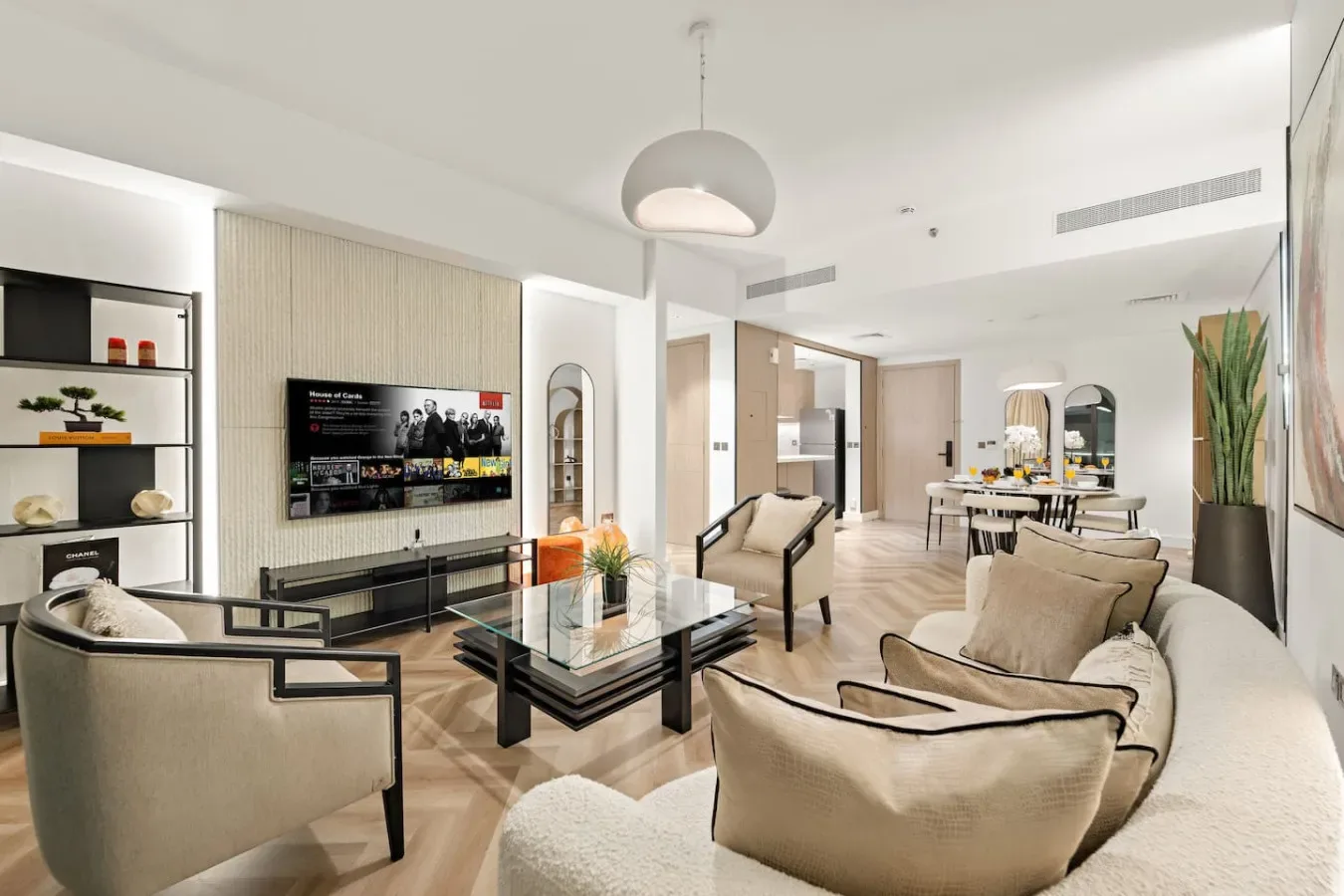 A bright living room with seating around a low coffee table and an open dining area.