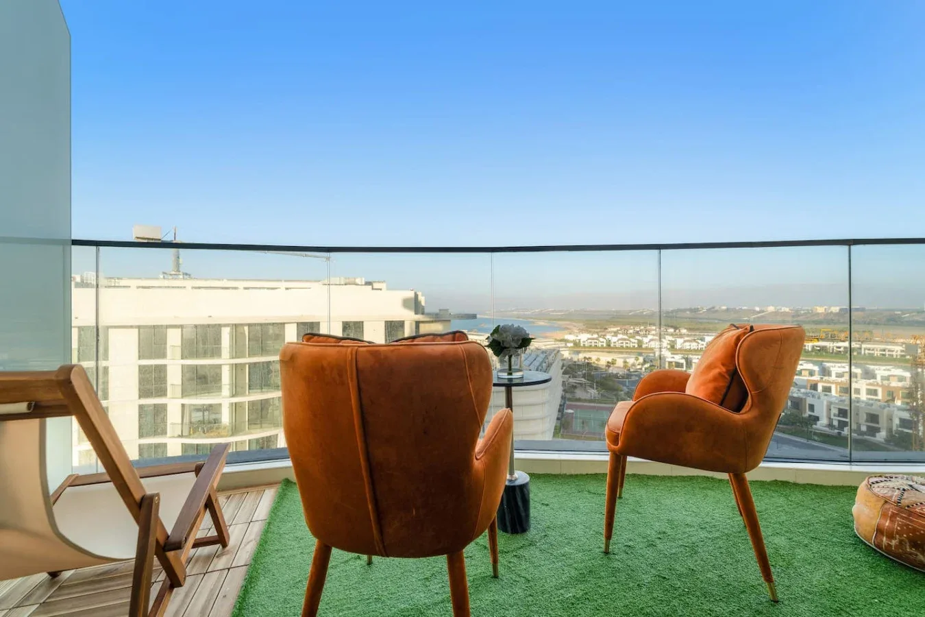 A balcony seating area overlooks nearby buildings and the distant landscape.