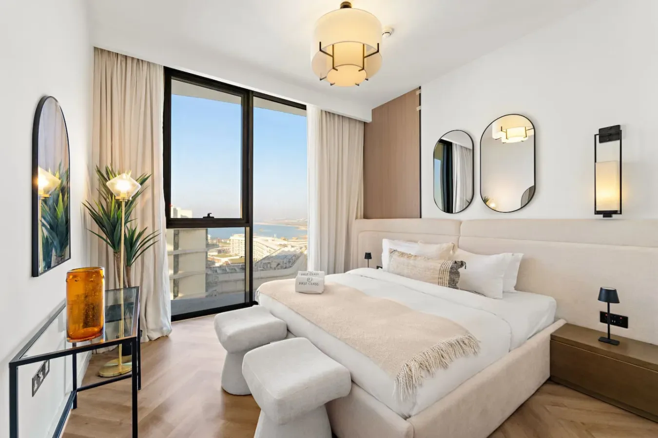 Un dormitorio luminoso con una cama grande junto a ventanales.