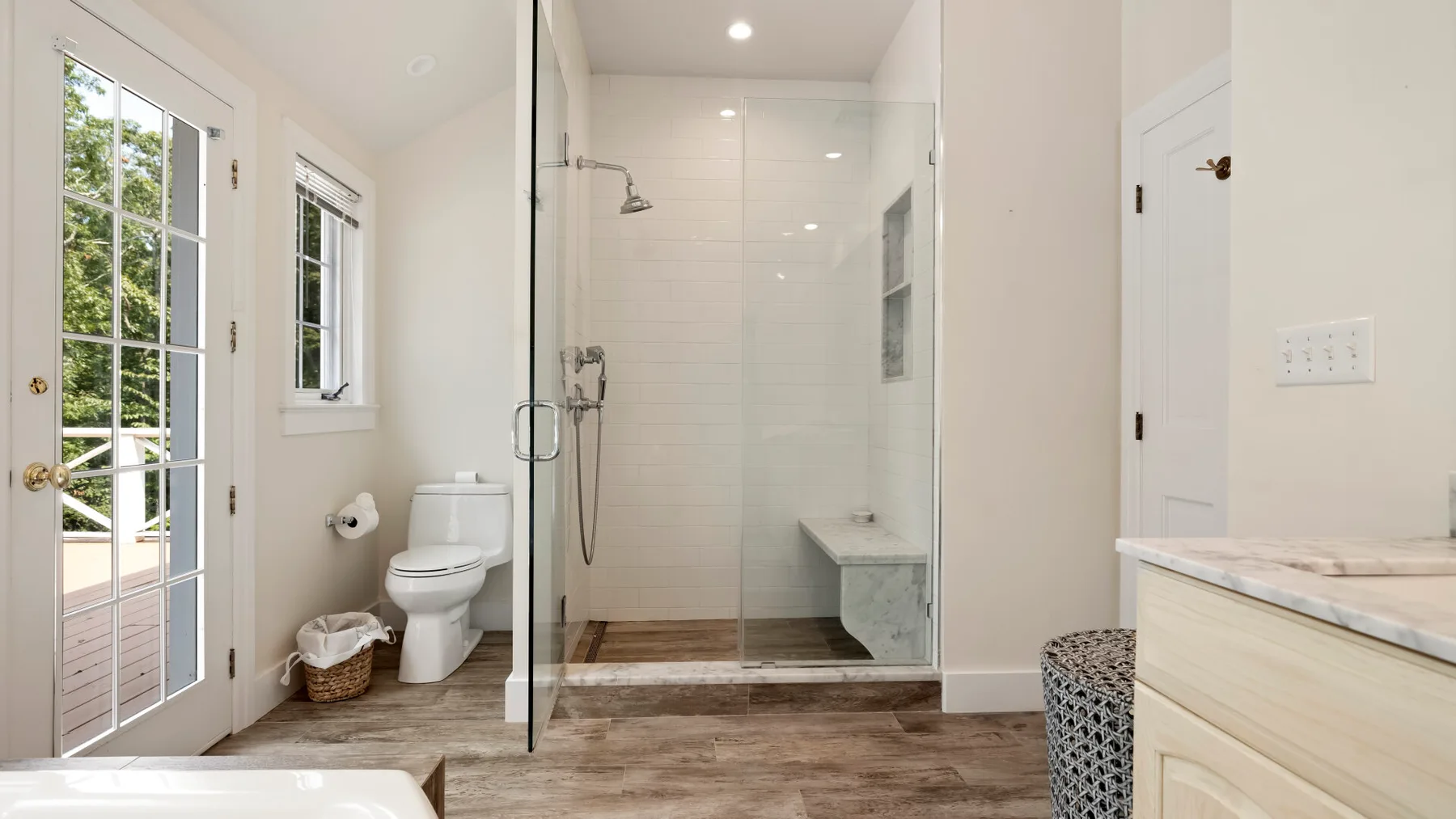 A bright bathroom with a glass-enclosed shower and a vanity.