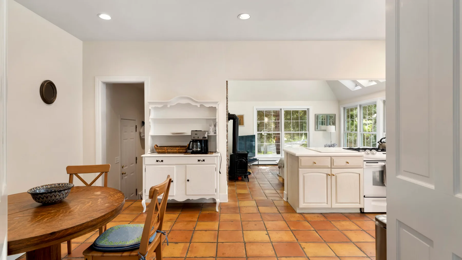 A bright kitchen and dining area with a wooden table and white cabinetry.