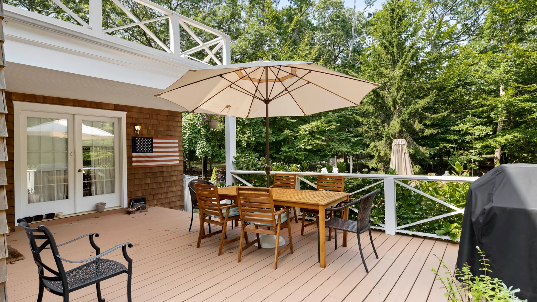 A wooden deck with outdoor seating beneath a large patio umbrella.