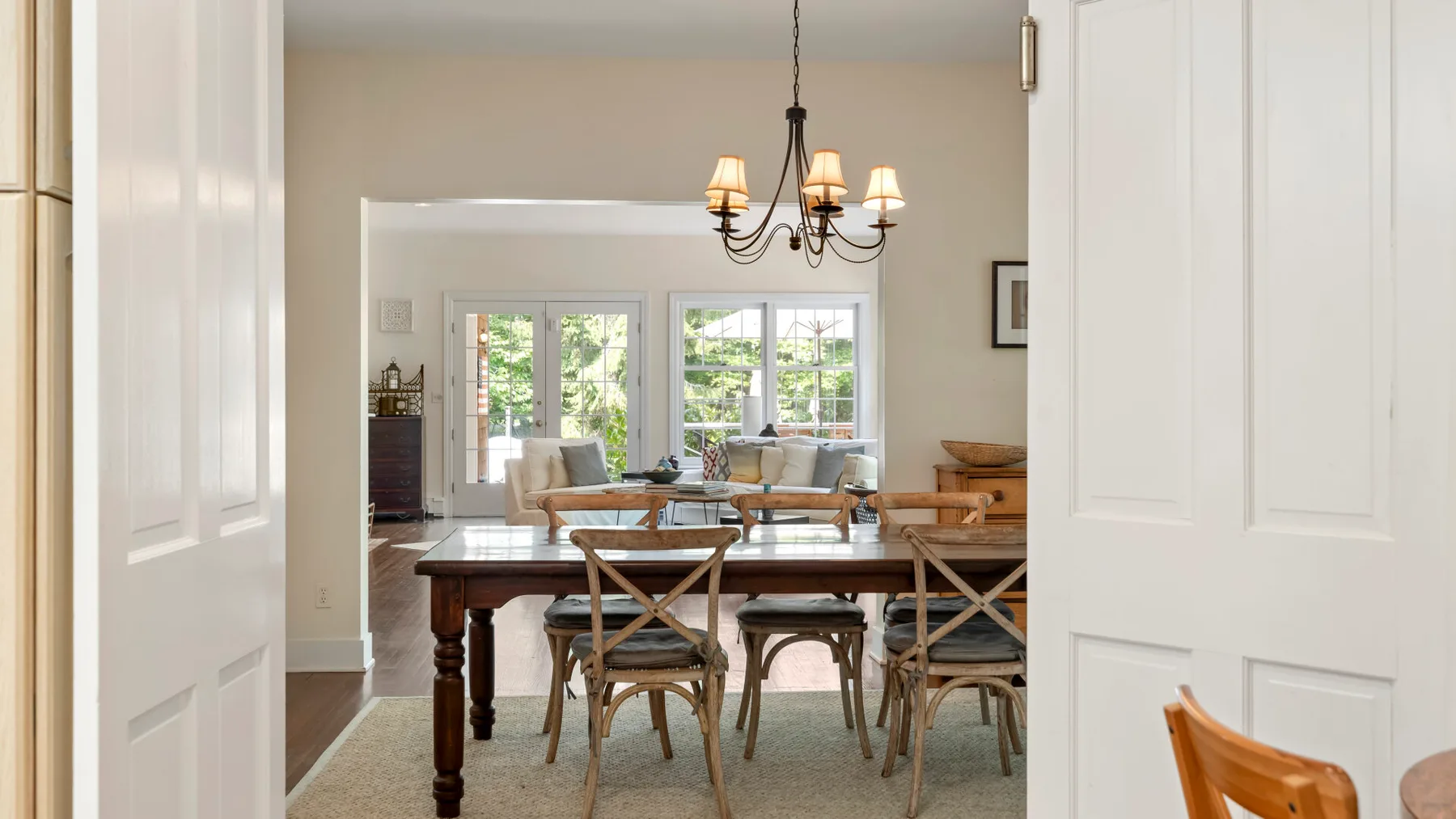 A dining room with a long wooden table and chairs beneath a chandelier.