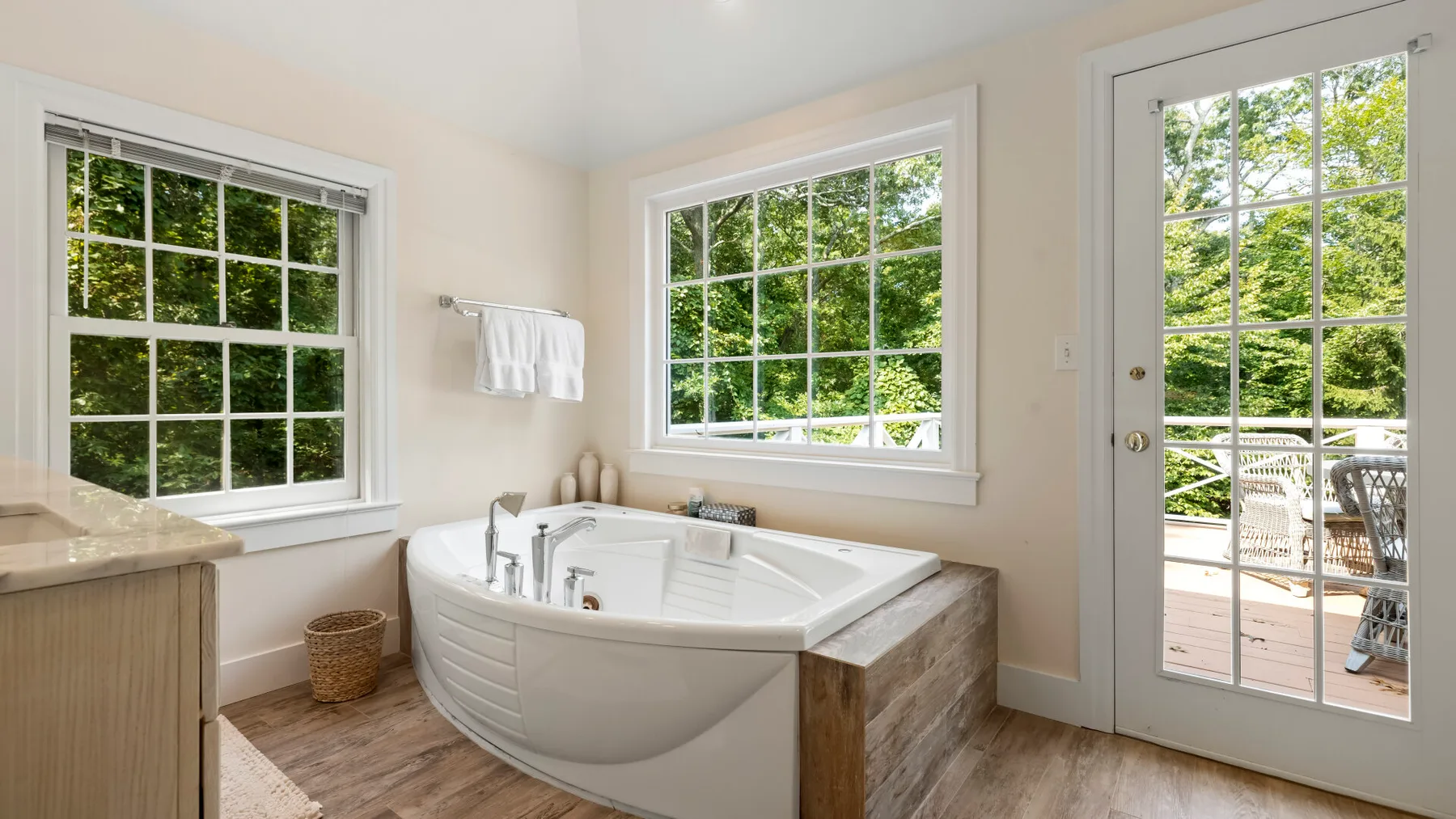 A bright bathroom features a corner bathtub beside large windows.