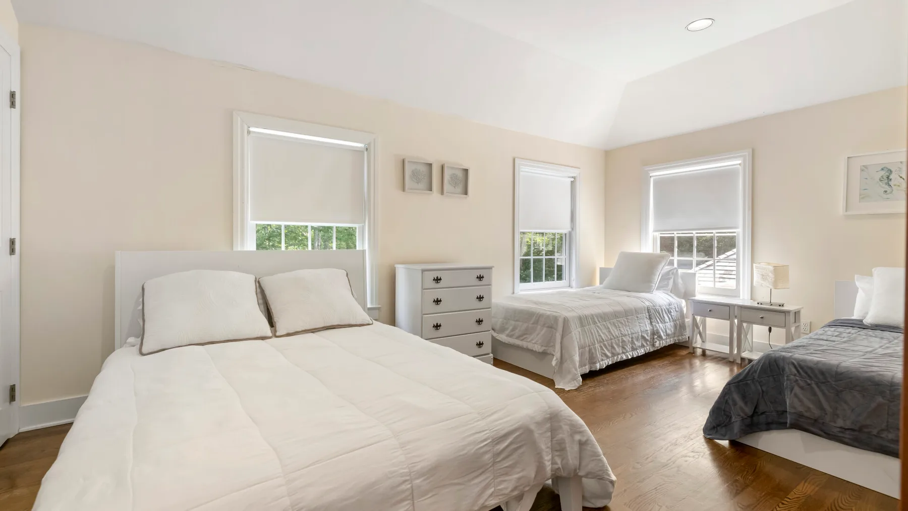 A bright bedroom with several beds and large windows.