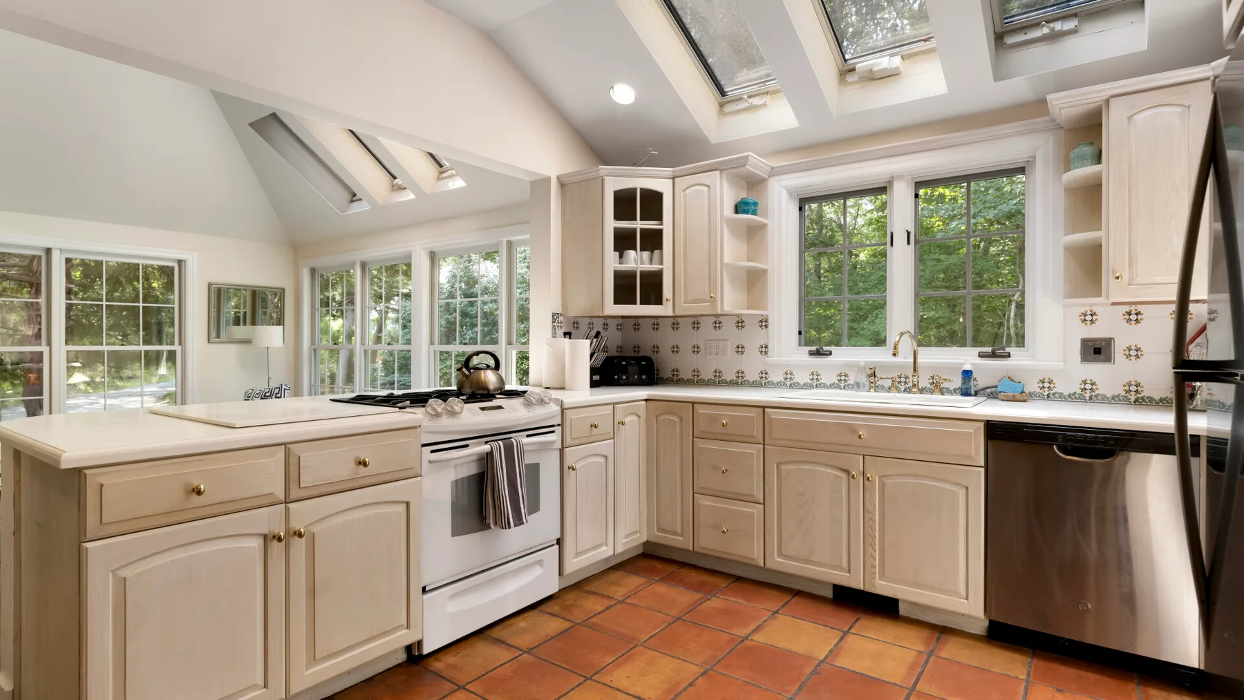 A bright kitchen with light cabinetry, wide windows, and skylights.