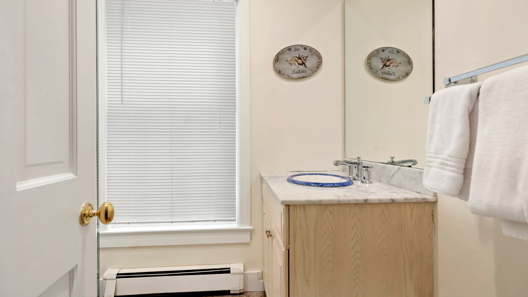 A bathroom vanity with a sink, mirror, and towel rack.