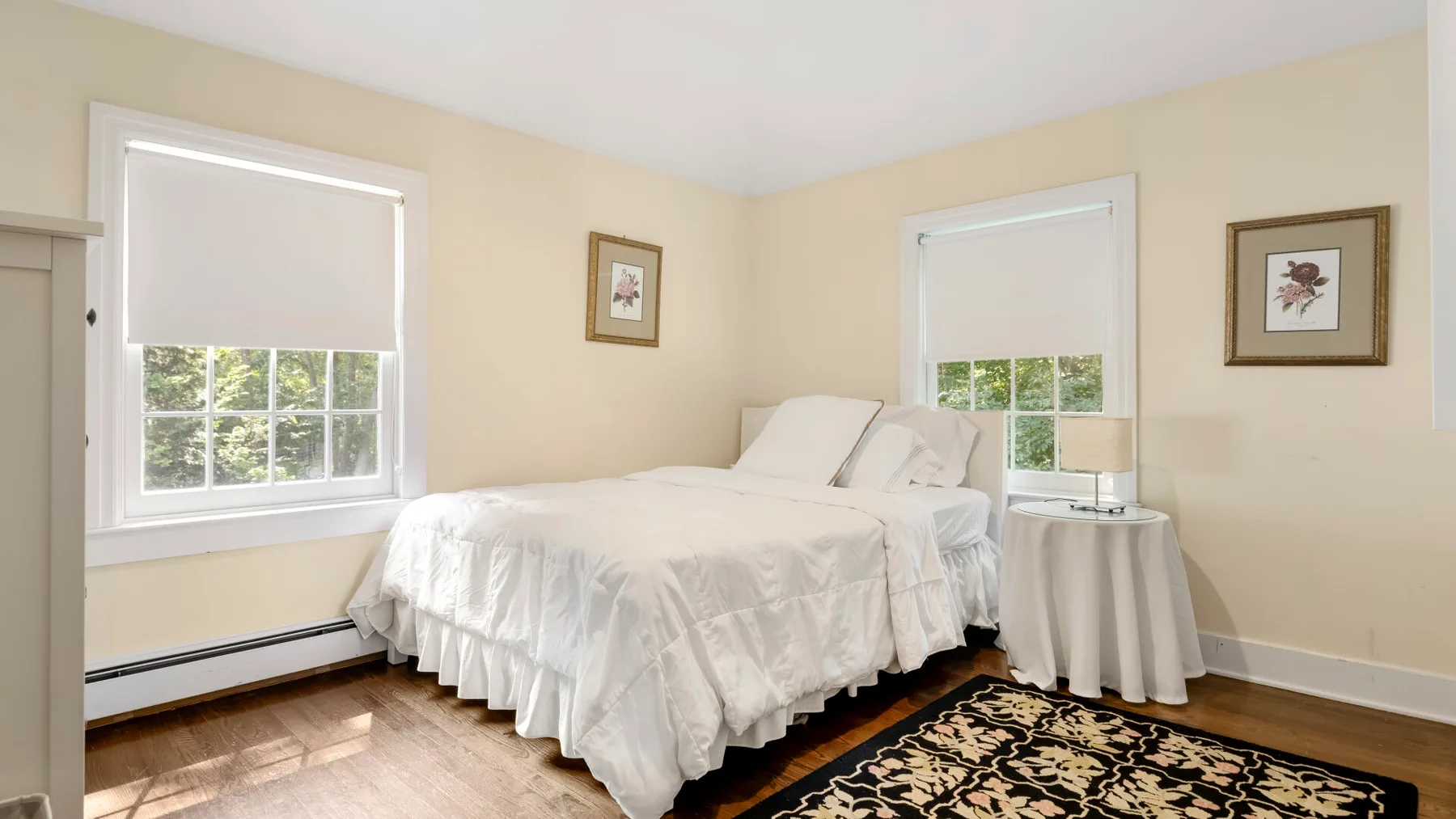 A bedroom with a bed, two windows, and a patterned rug.