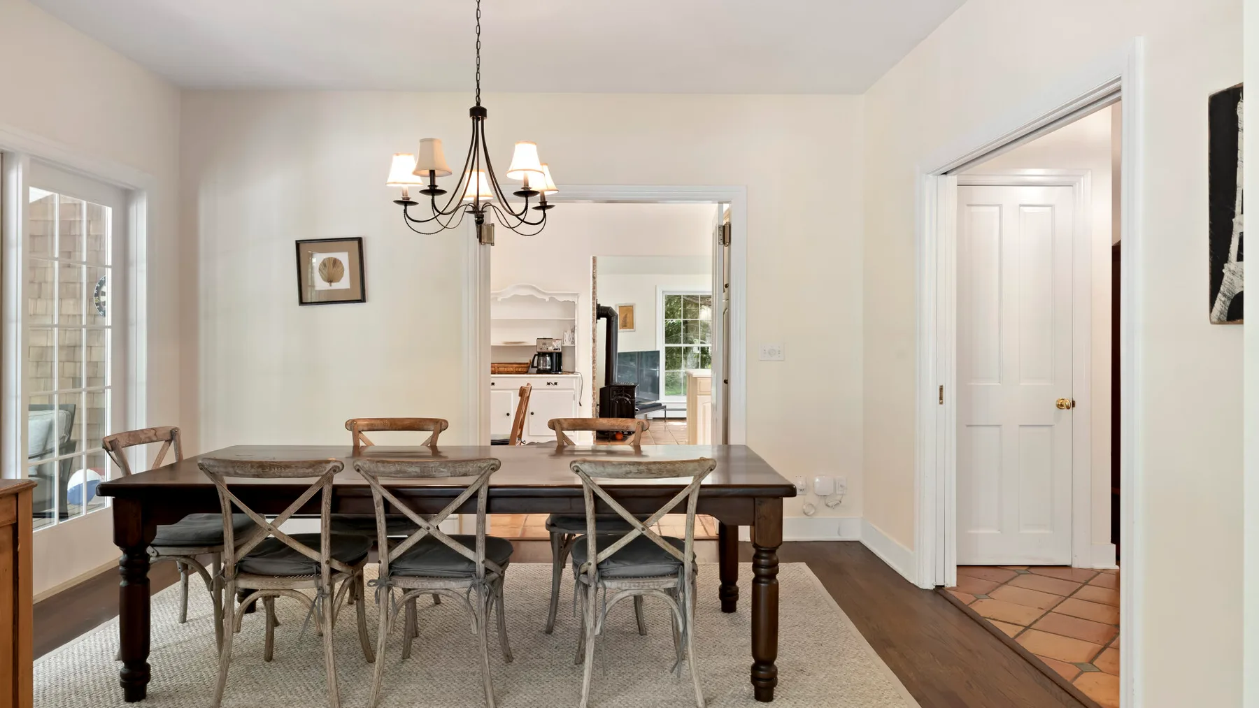 A dining room with a long table and chairs beneath a chandelier.
