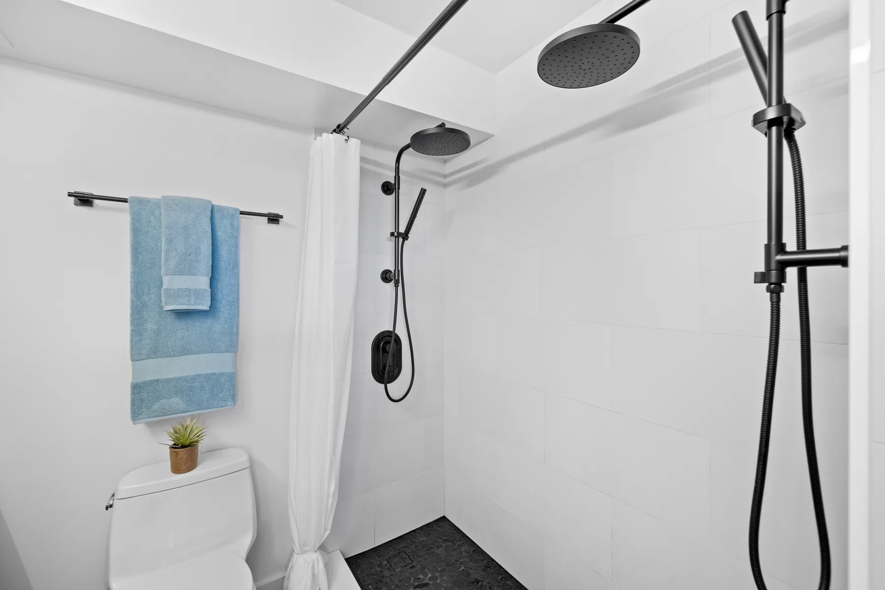 Un baño luminoso con ducha y una toalla colgada cerca.