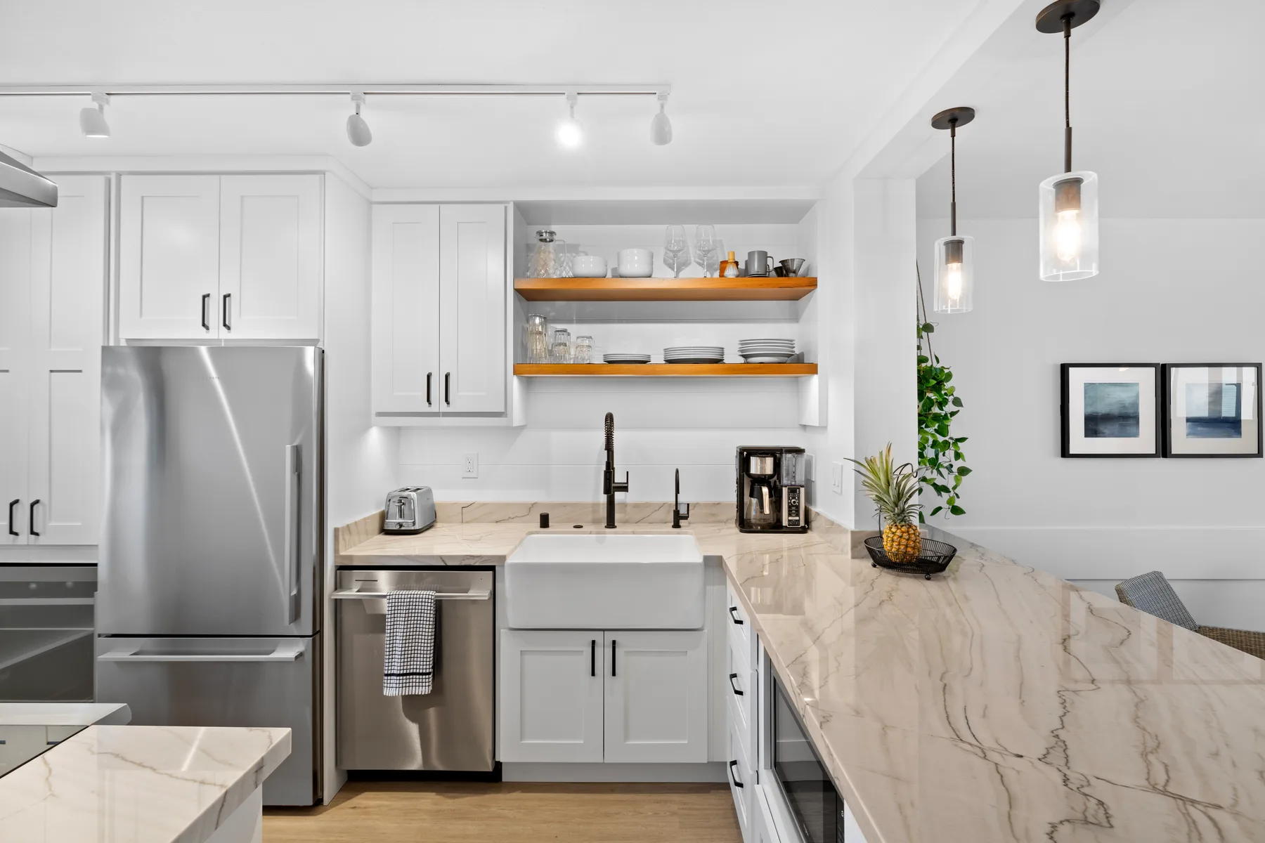 Una cocina luminosa con gabinetes blancos y una gran isla de piedra.