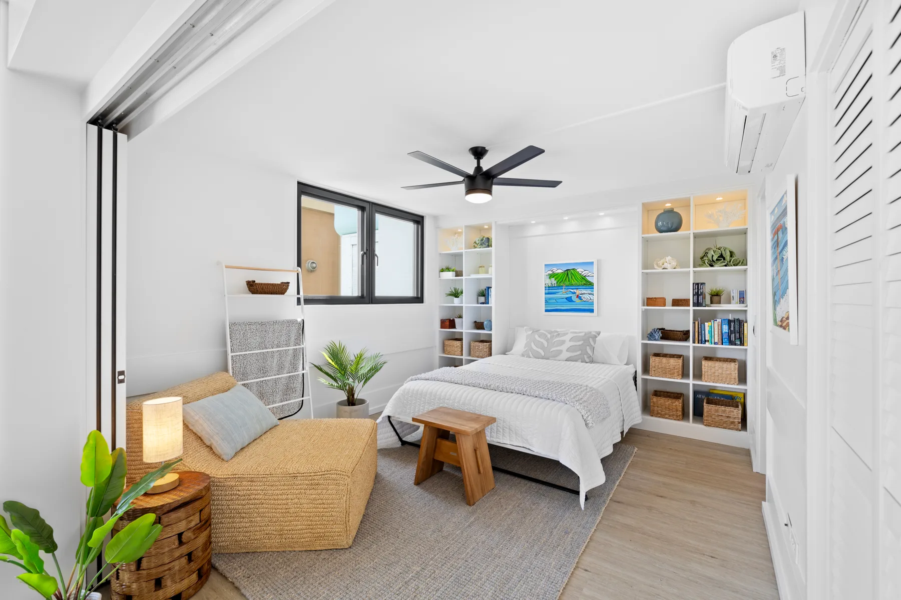 Un dormitorio luminoso con una cama, asientos tejidos y estanterías empotradas.