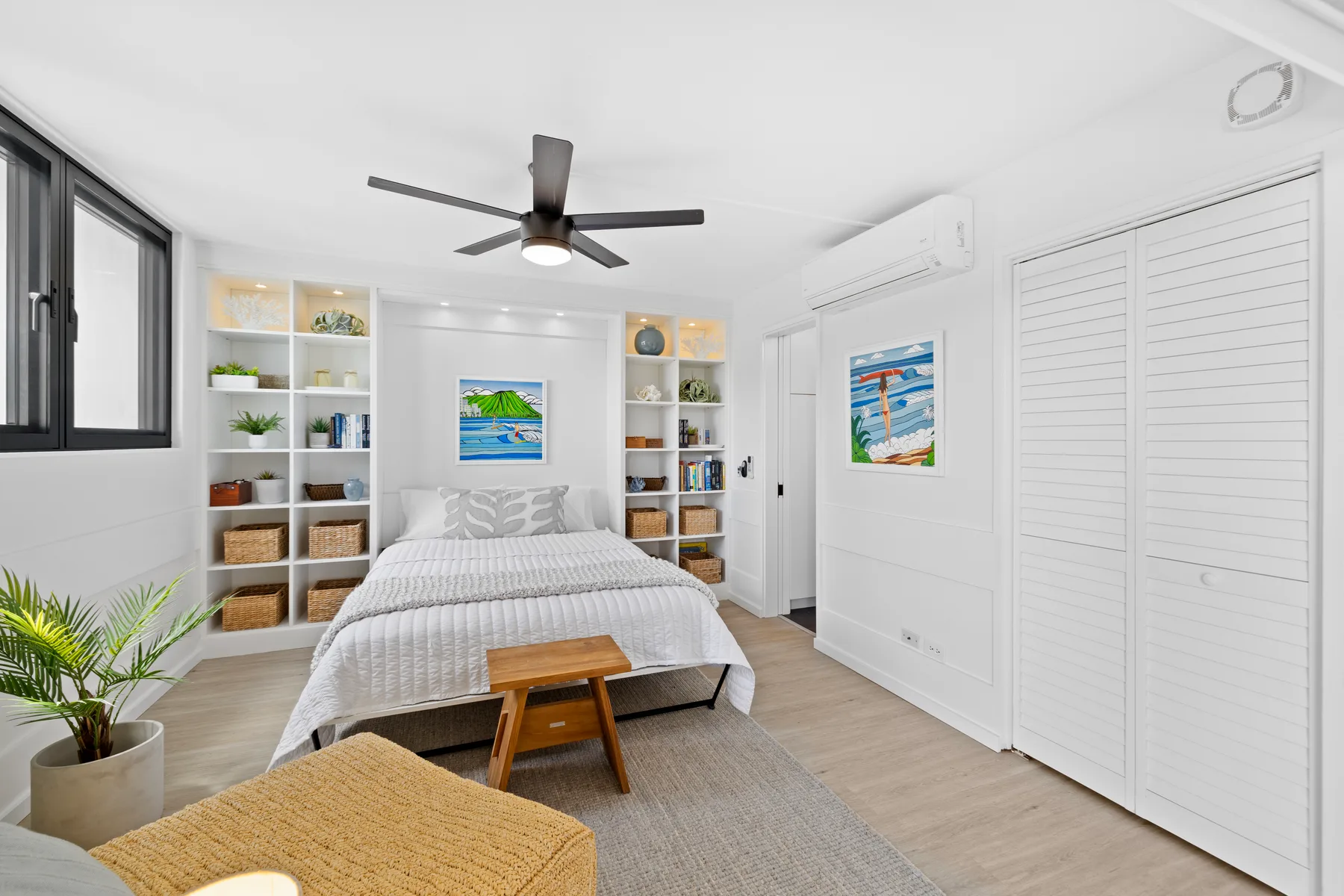 Un dormitorio luminoso con cama, estantes empotrados y ventilador de techo.