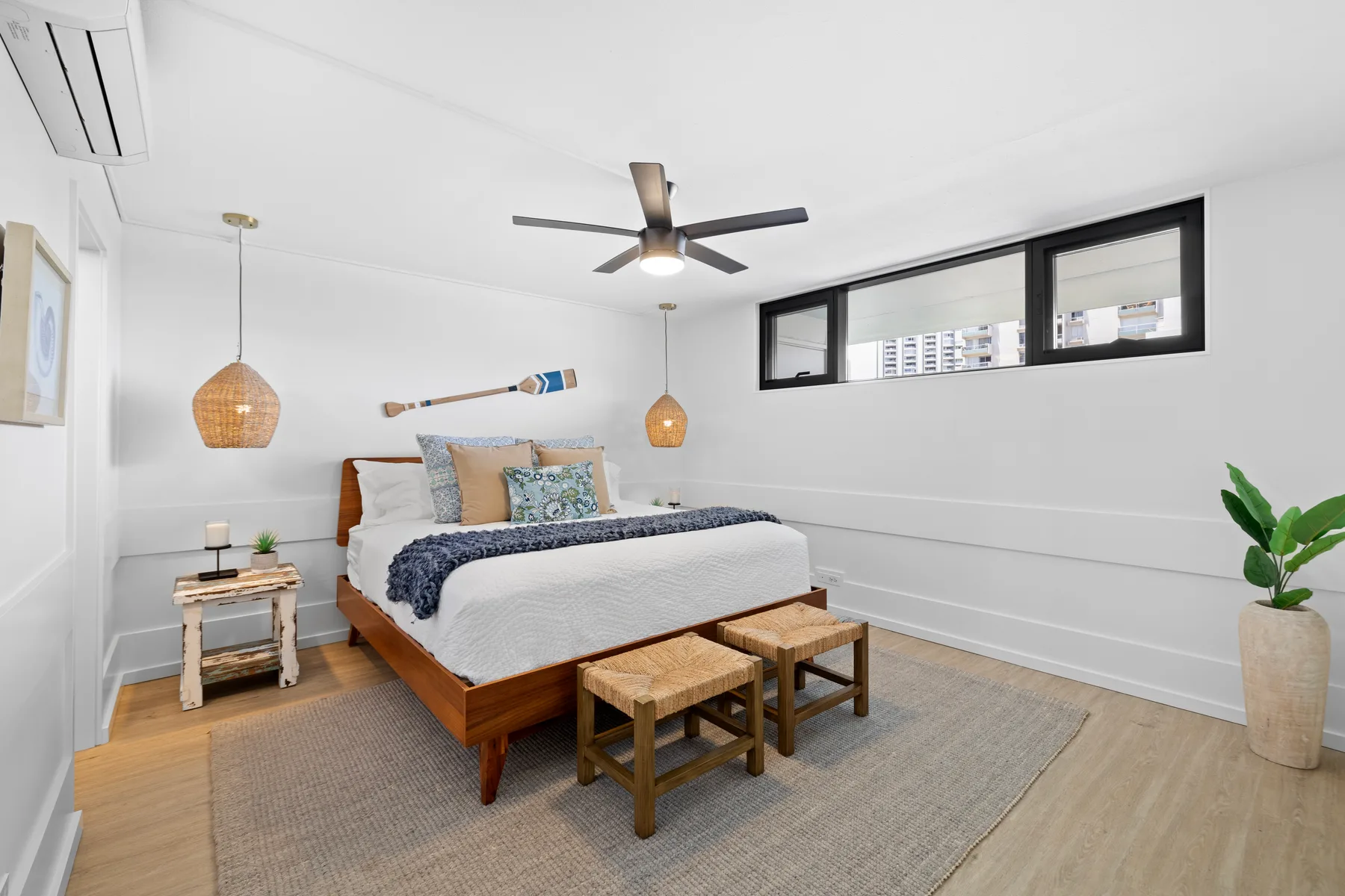 Un dormitorio luminoso con una cama de madera, lámparas colgantes tejidas y un ventilador de techo.