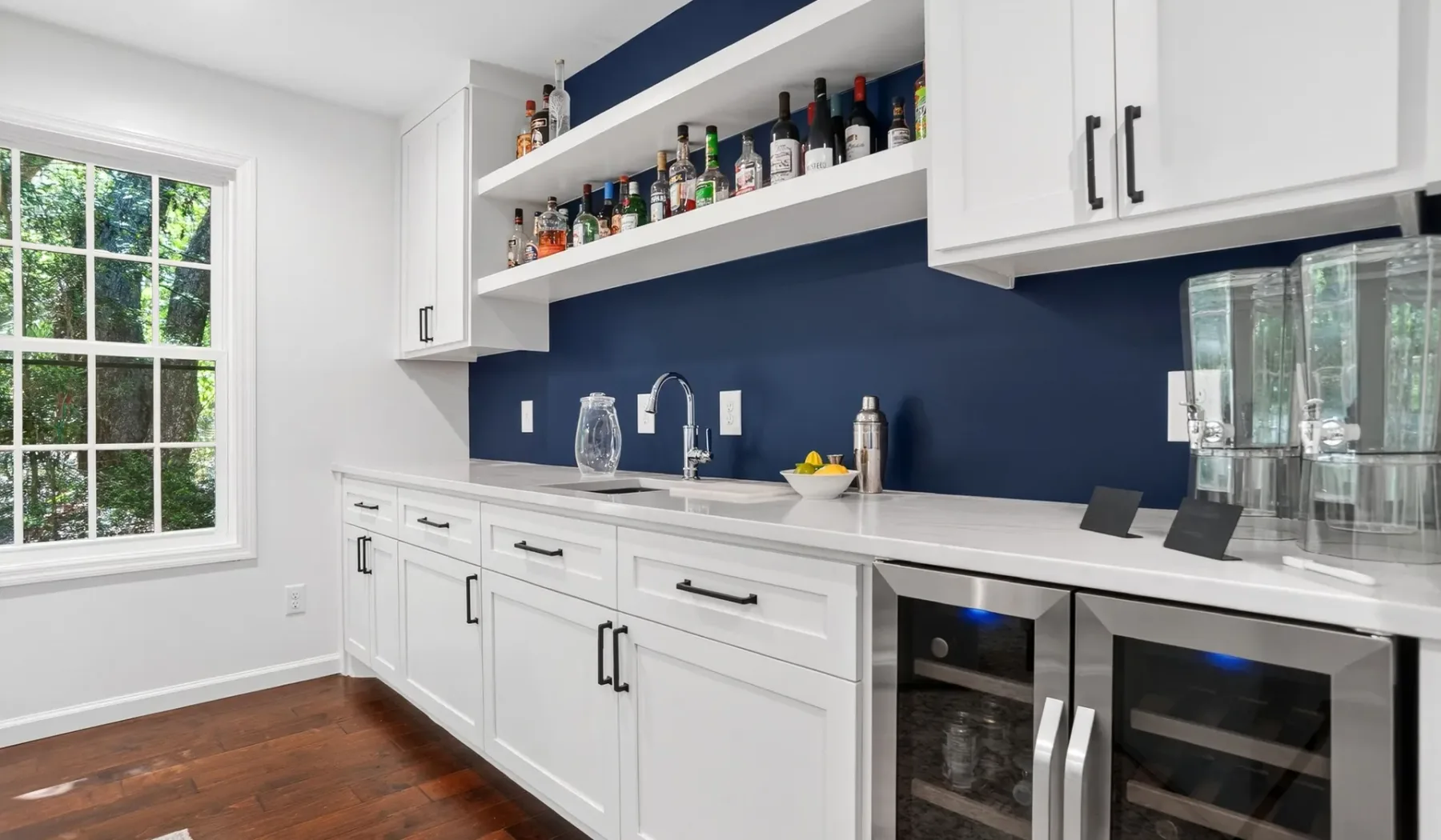 A bright bar area with a long counter, shelves, and beverage refrigerators.