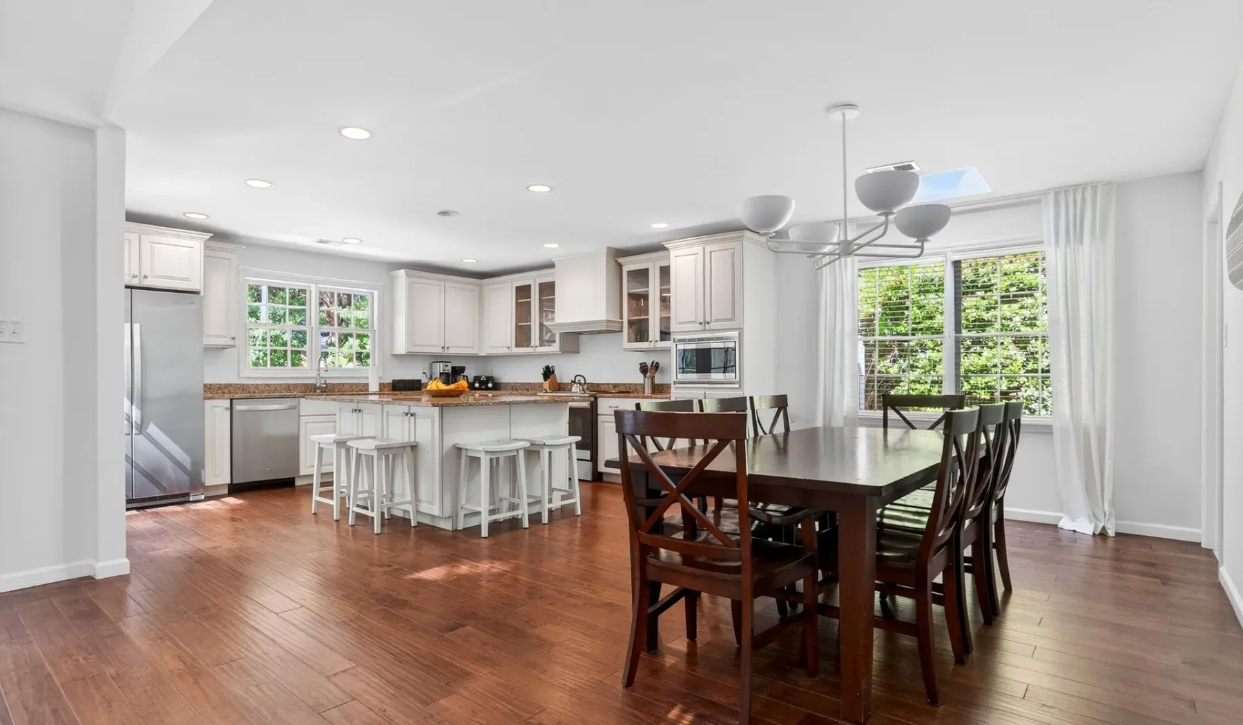 Open-plan kitchen and dining area with a large table beside the windows.