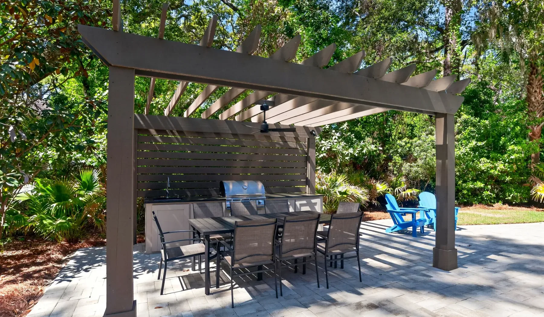 An outdoor patio with a shaded dining area and blue lounge chairs.