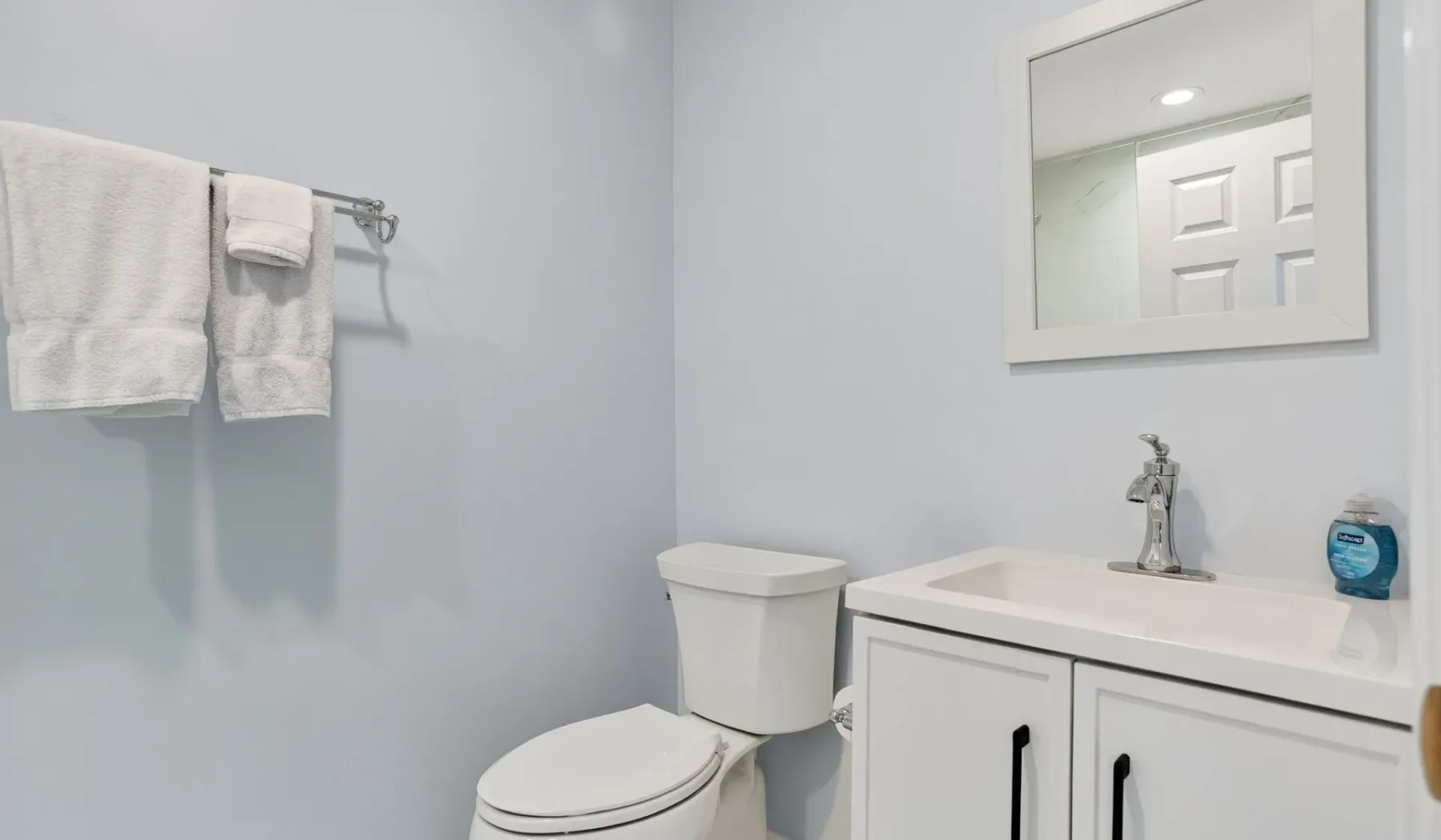 A bathroom with a toilet, sink, and towels hanging on the wall.