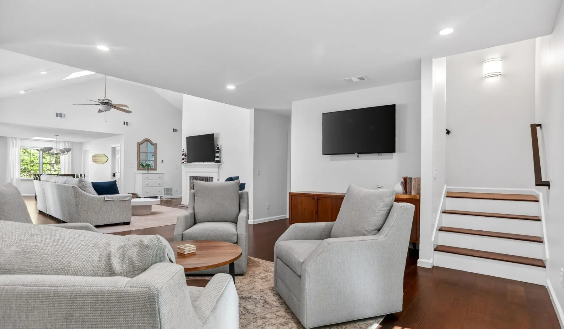 A bright living room with light-colored seating arranged around a wooden coffee table.