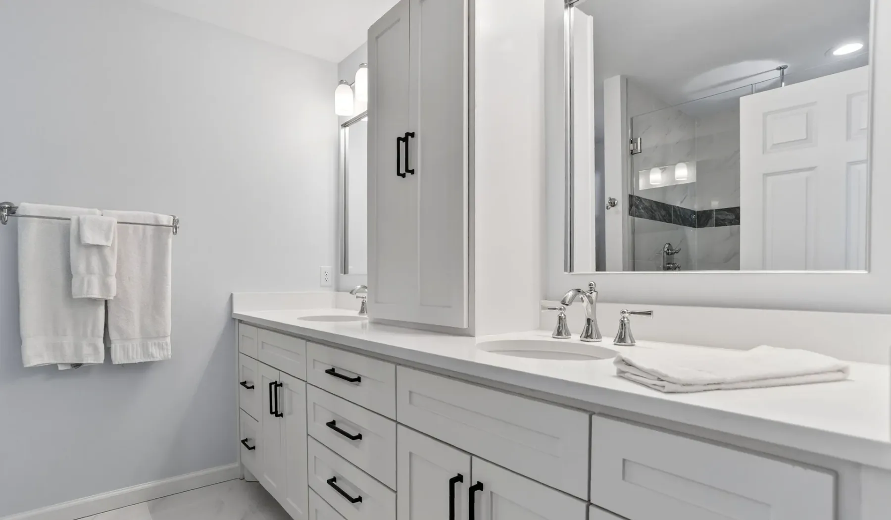 A bright bathroom with a long vanity, sink, and wall mirror.