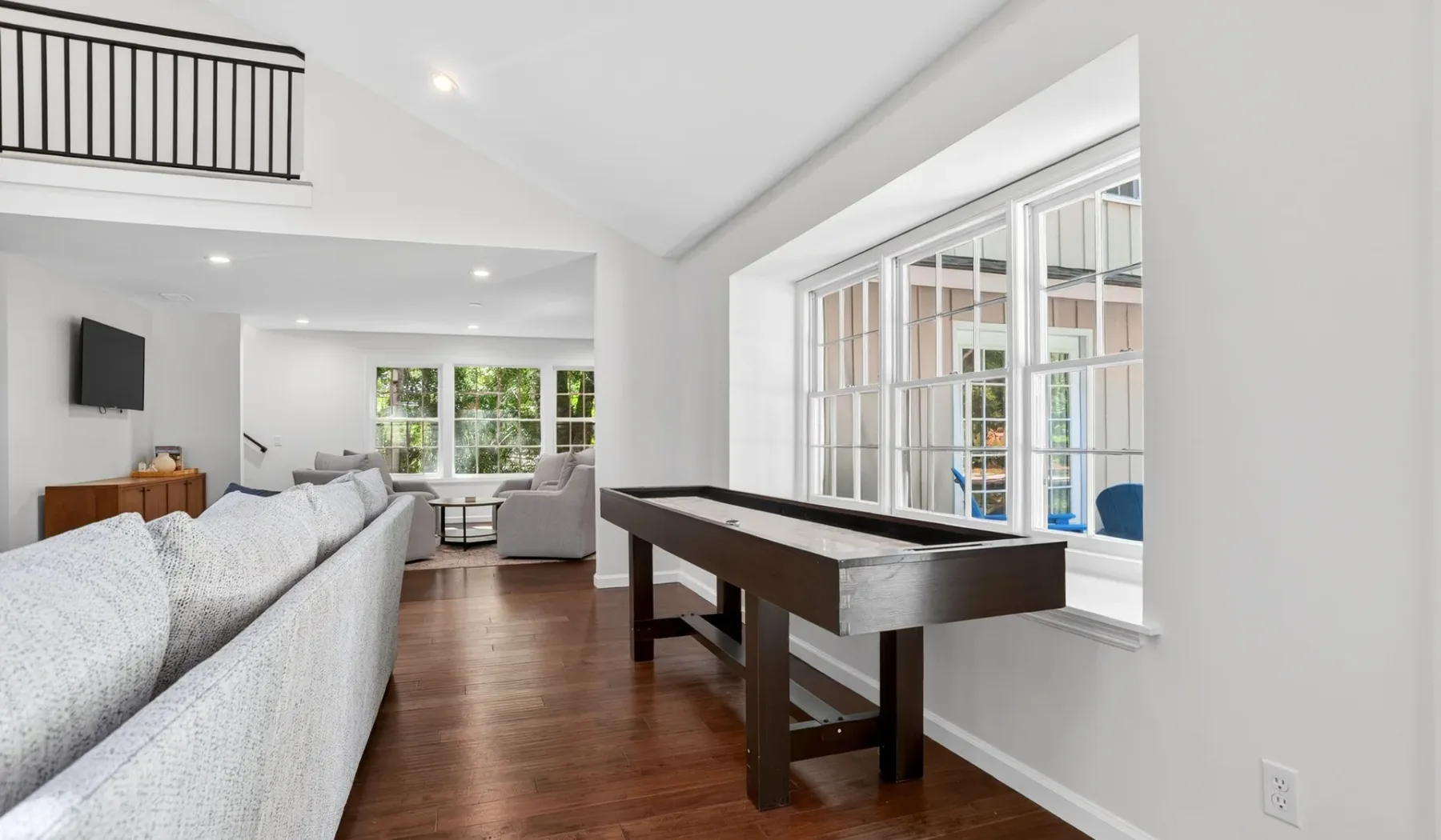 A bright living room with seating and a pool table beside large windows.