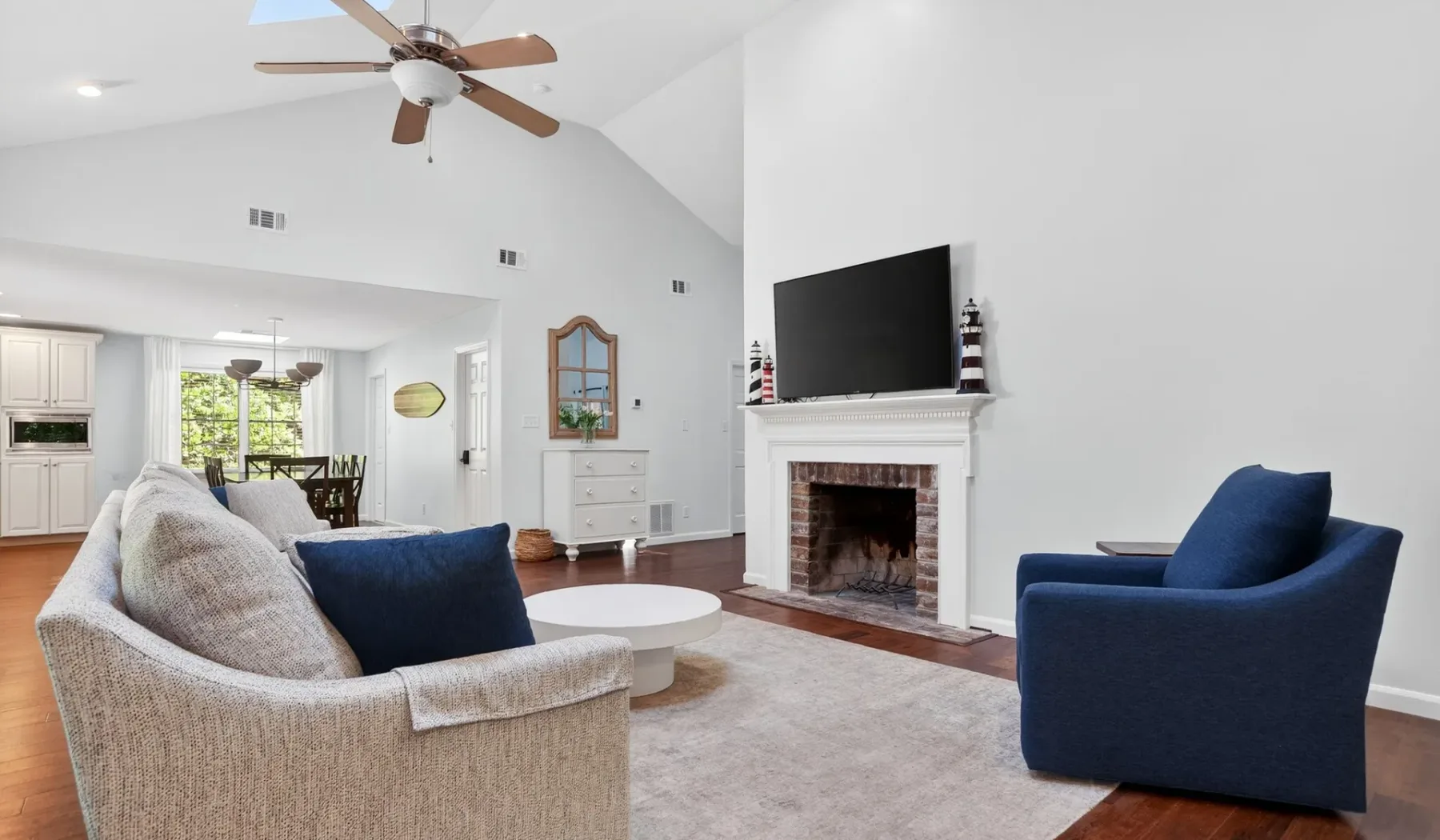 A bright living room with seating arranged around a fireplace and television.