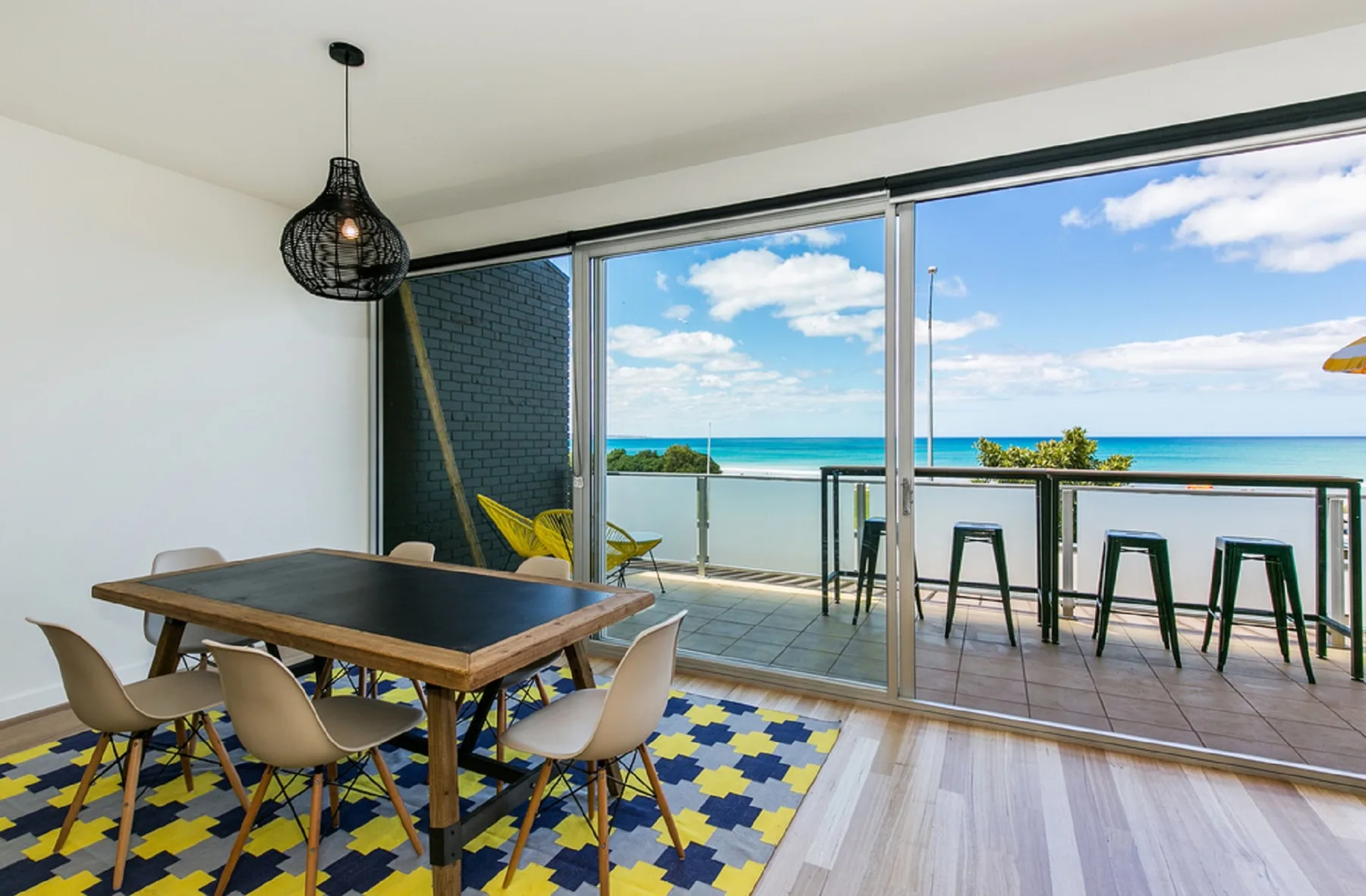 A dining area opens onto a balcony with a view of the ocean.