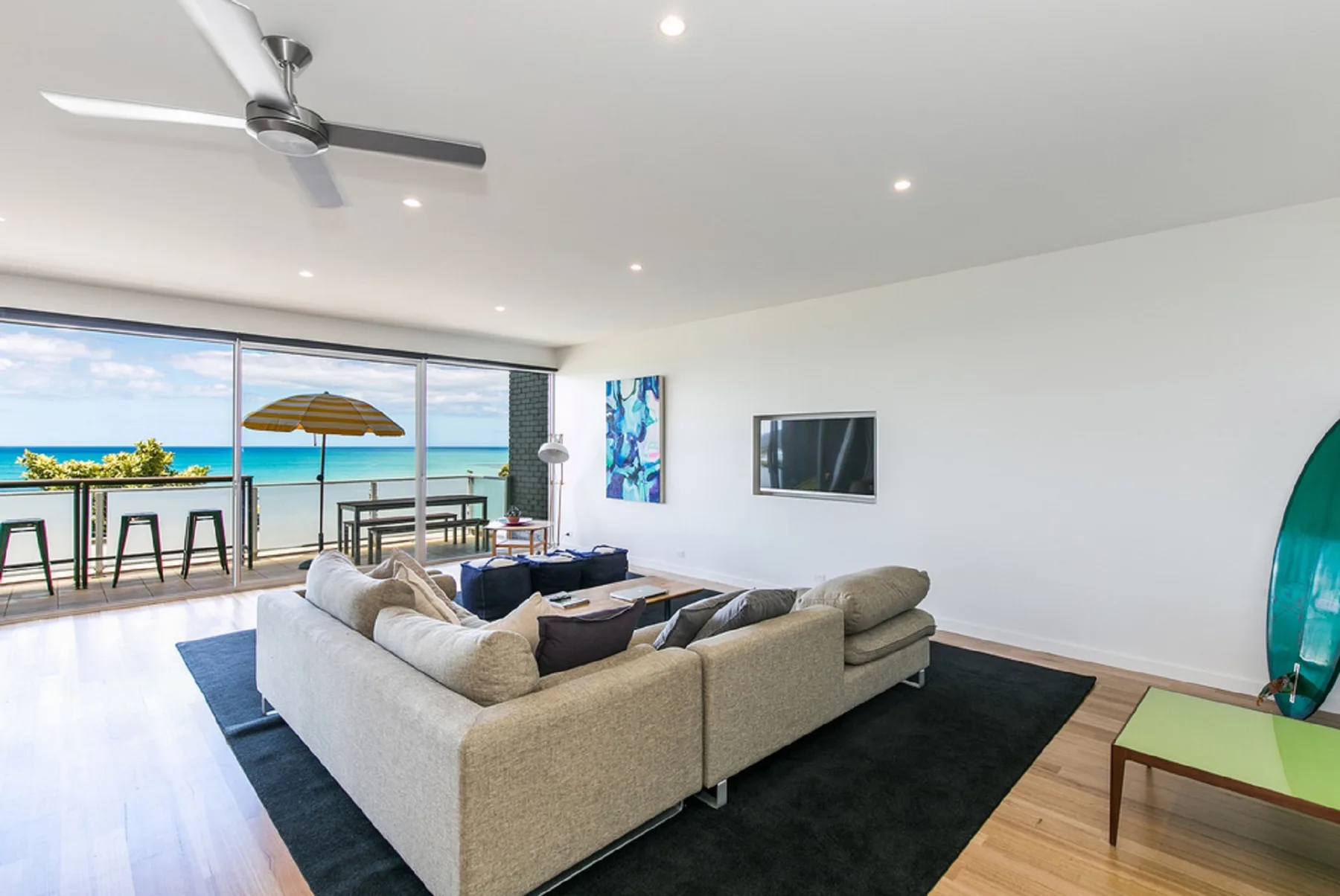 A bright living room opens onto a balcony with ocean views.